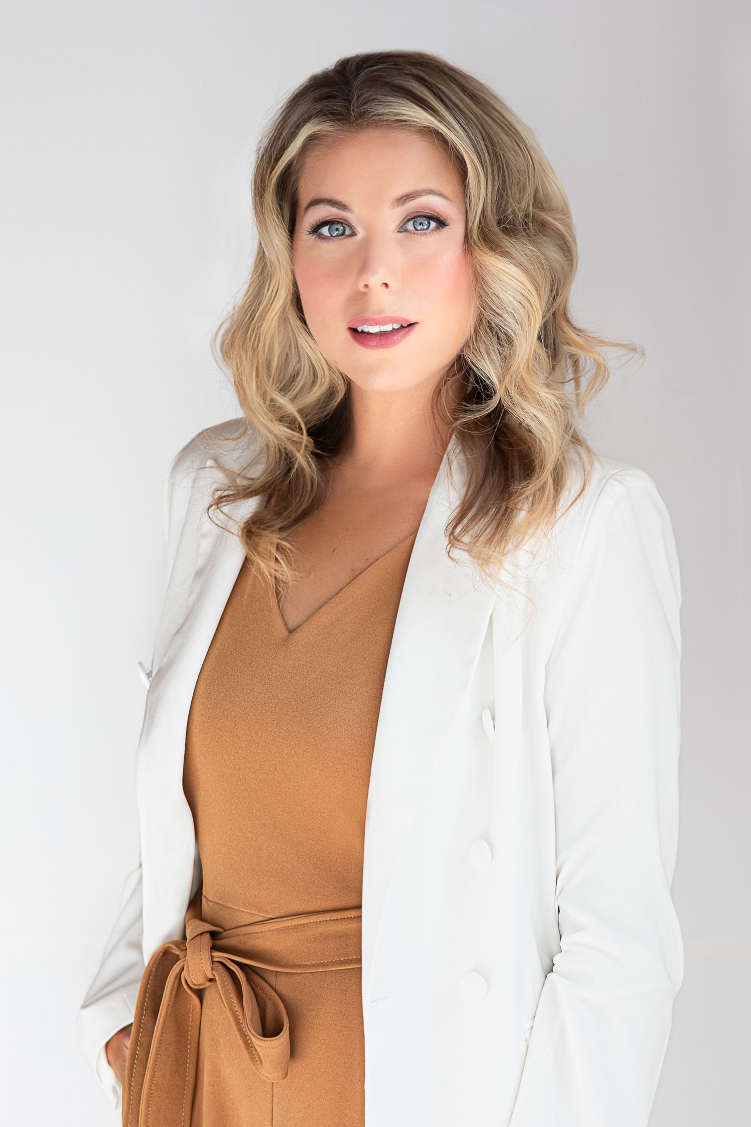 Professional studio portraits in white blazer and camel top against light background.