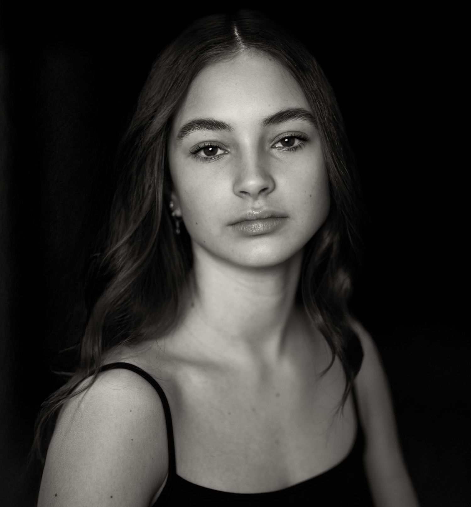 Dramatic black and white portrait series with moody lighting and dark background.