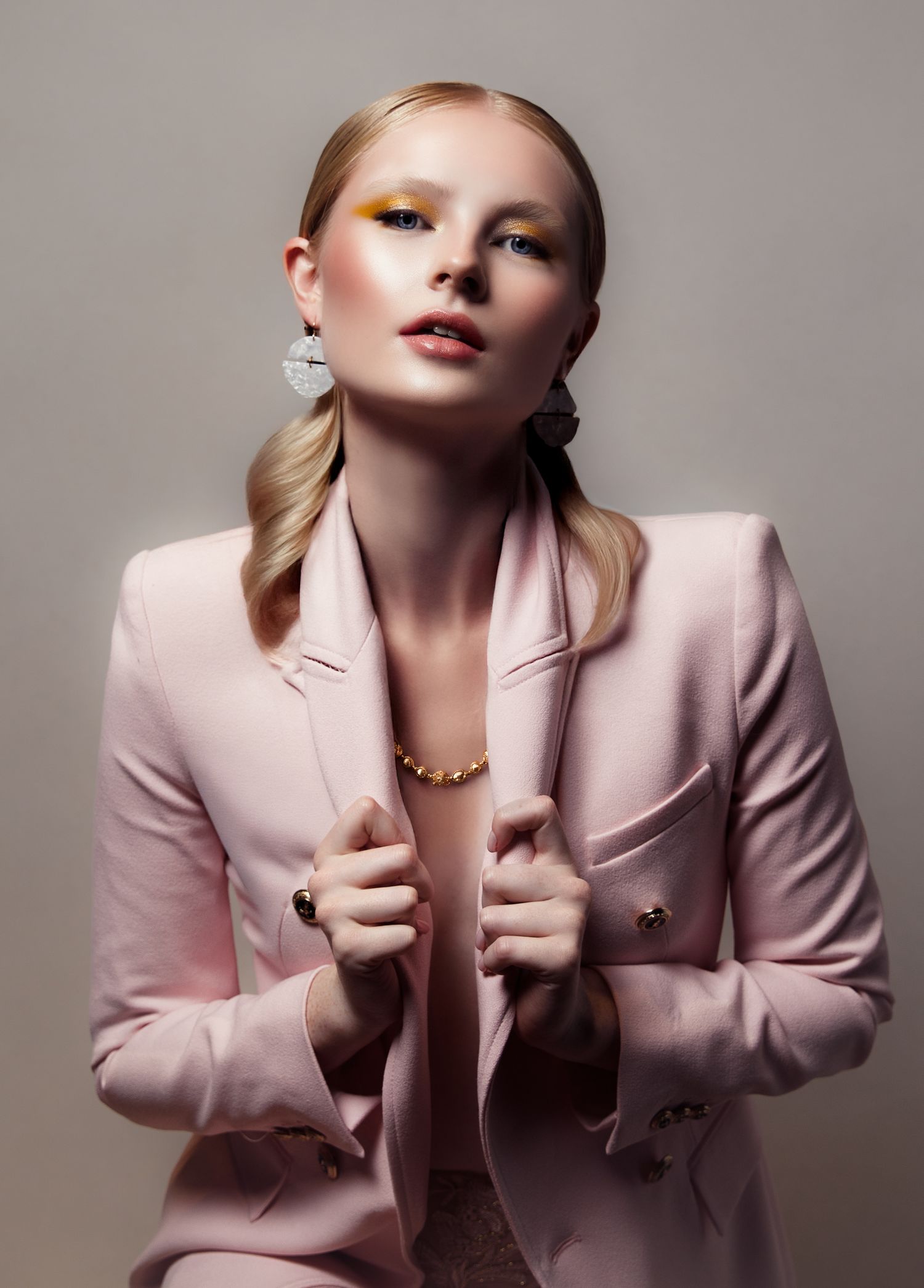 Fashion portrait series featuring a light pink blazer styled in different dramatic poses against a neutral background.