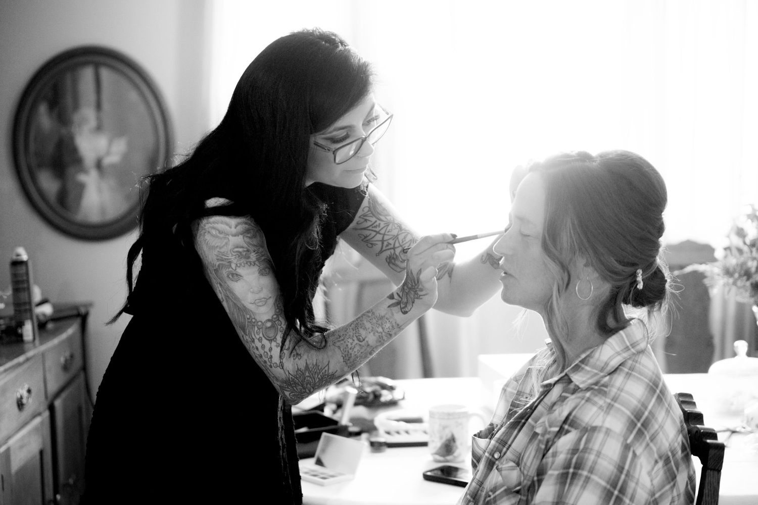Black and white photo of makeup application session in morning light.