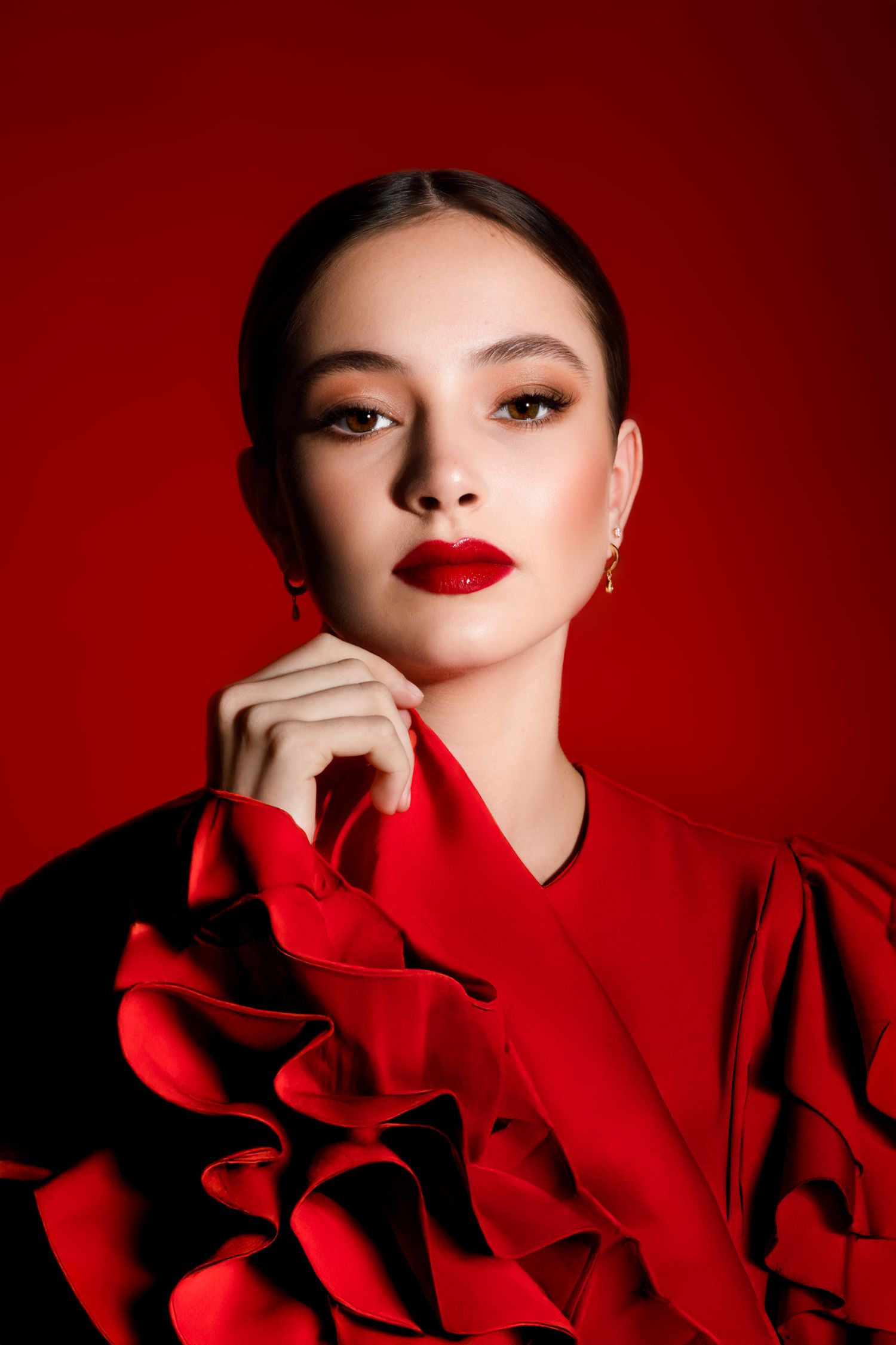 Dramatic fashion portraits in red featuring bold lipstick and ruffled clothing details against a crimson background.