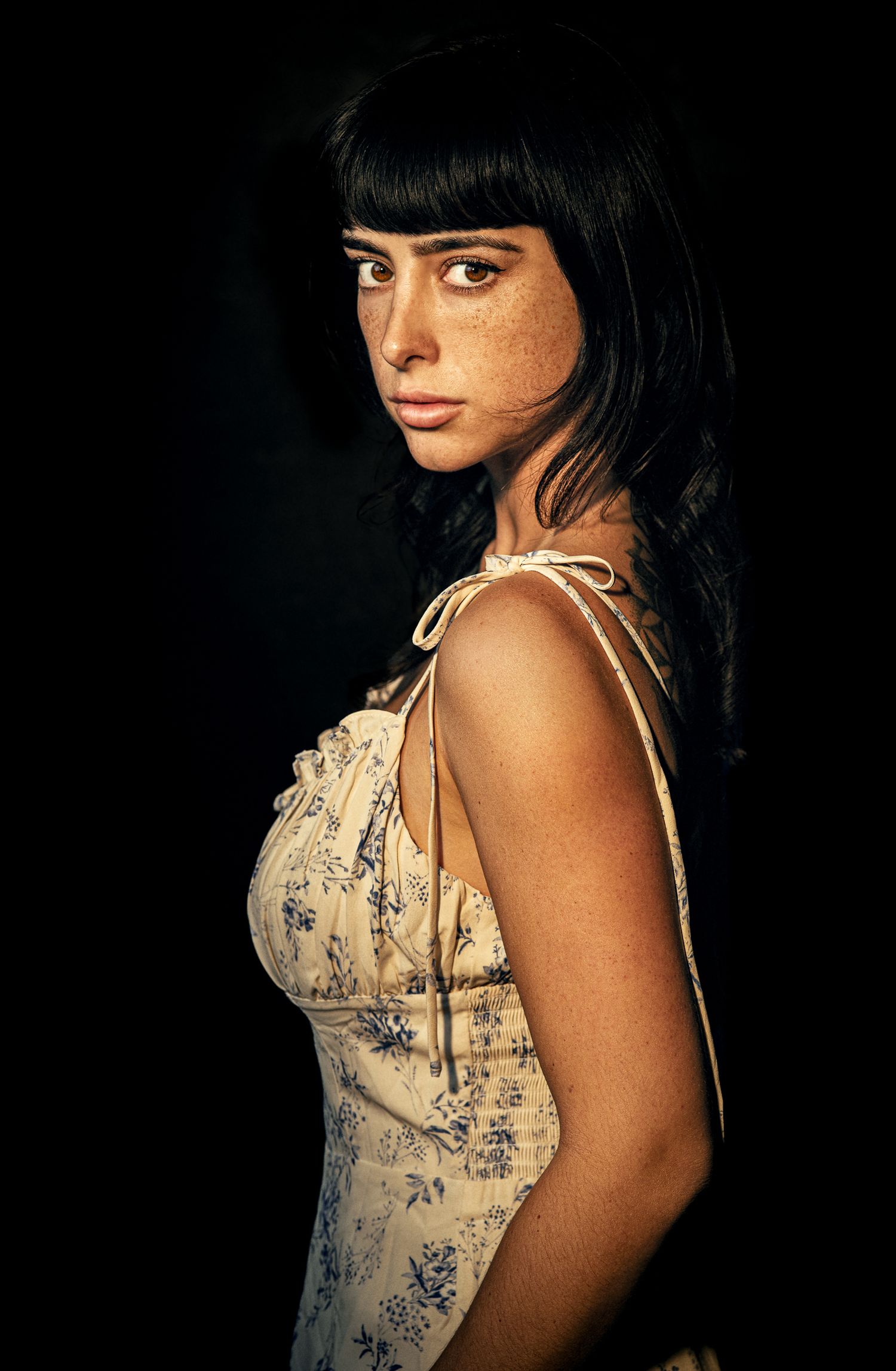 Moody portraits in floral dress with dramatic side lighting.