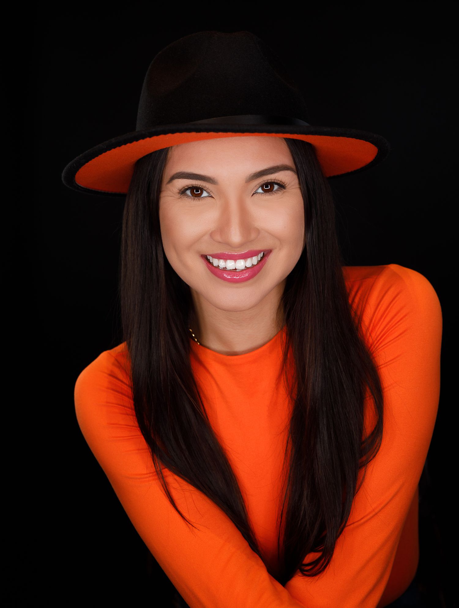 Fashion portraits featuring bright orange attire and black hat with expressive poses.