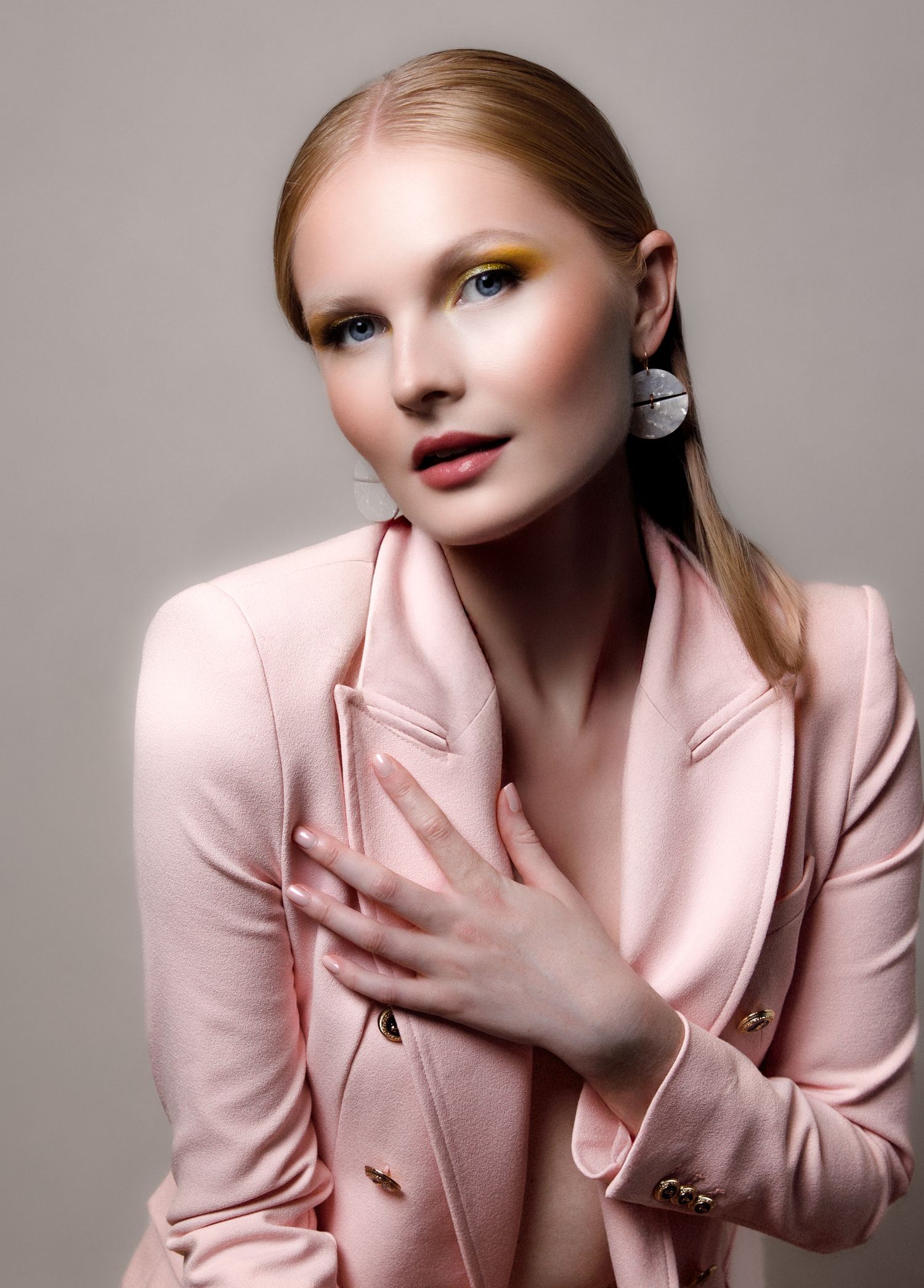 Fashion portrait series in pink blazer featuring dramatic makeup and styling against neutral backdrop.