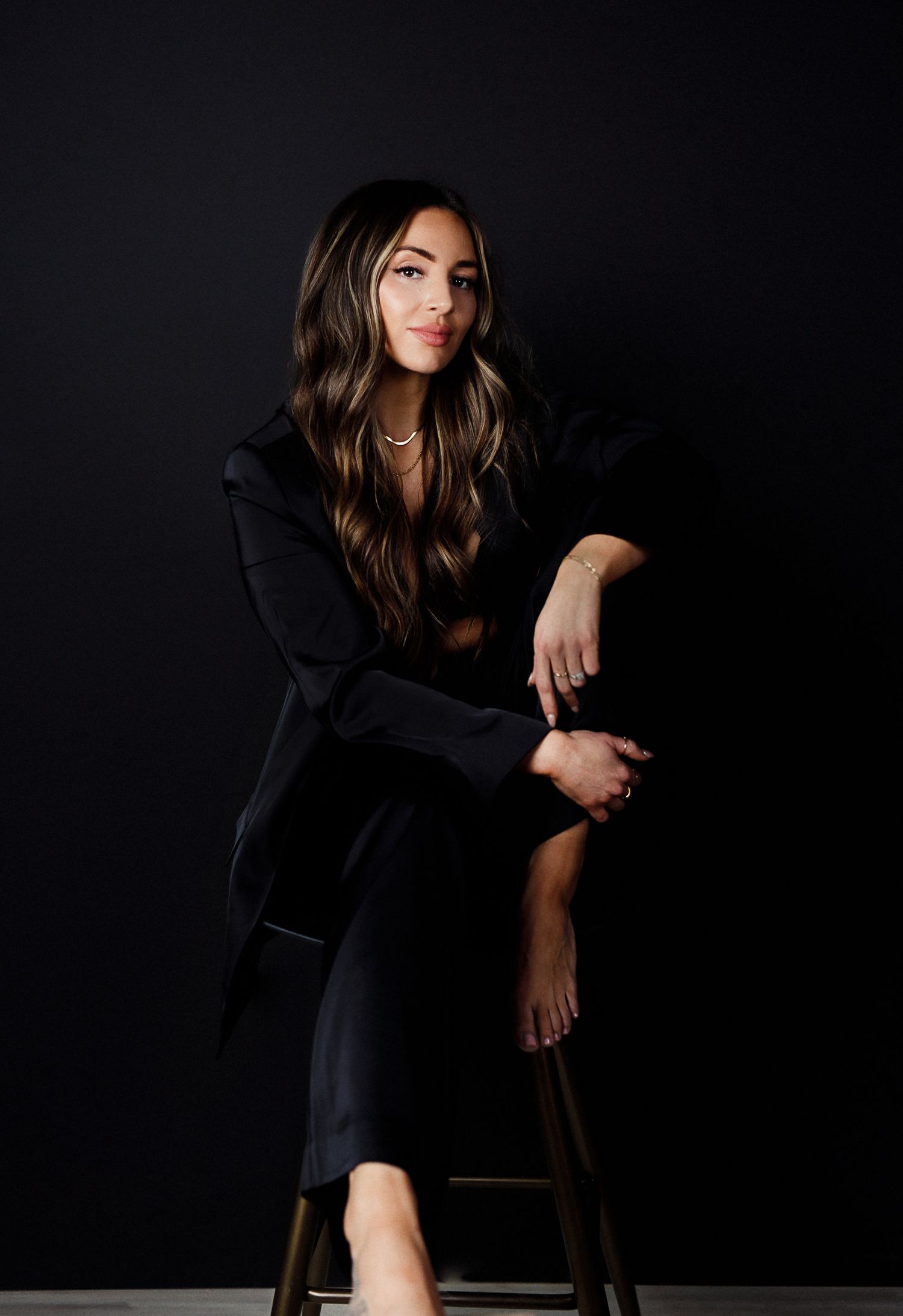 Dramatic dark studio portraits showing artistic poses on wooden stool.