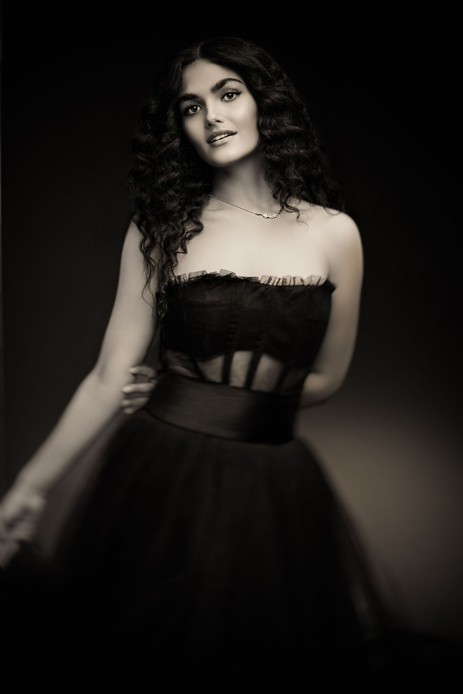 Vintage-style portrait in black strapless dress with corset detail against dark background.