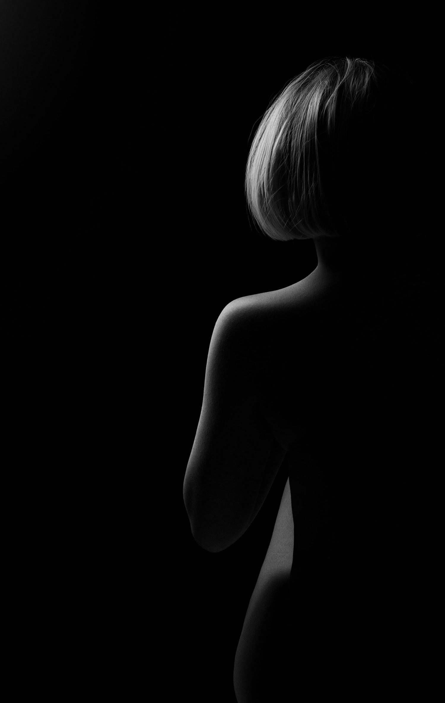 Black and white artistic silhouette of a woman with short blonde hair against a dark background.