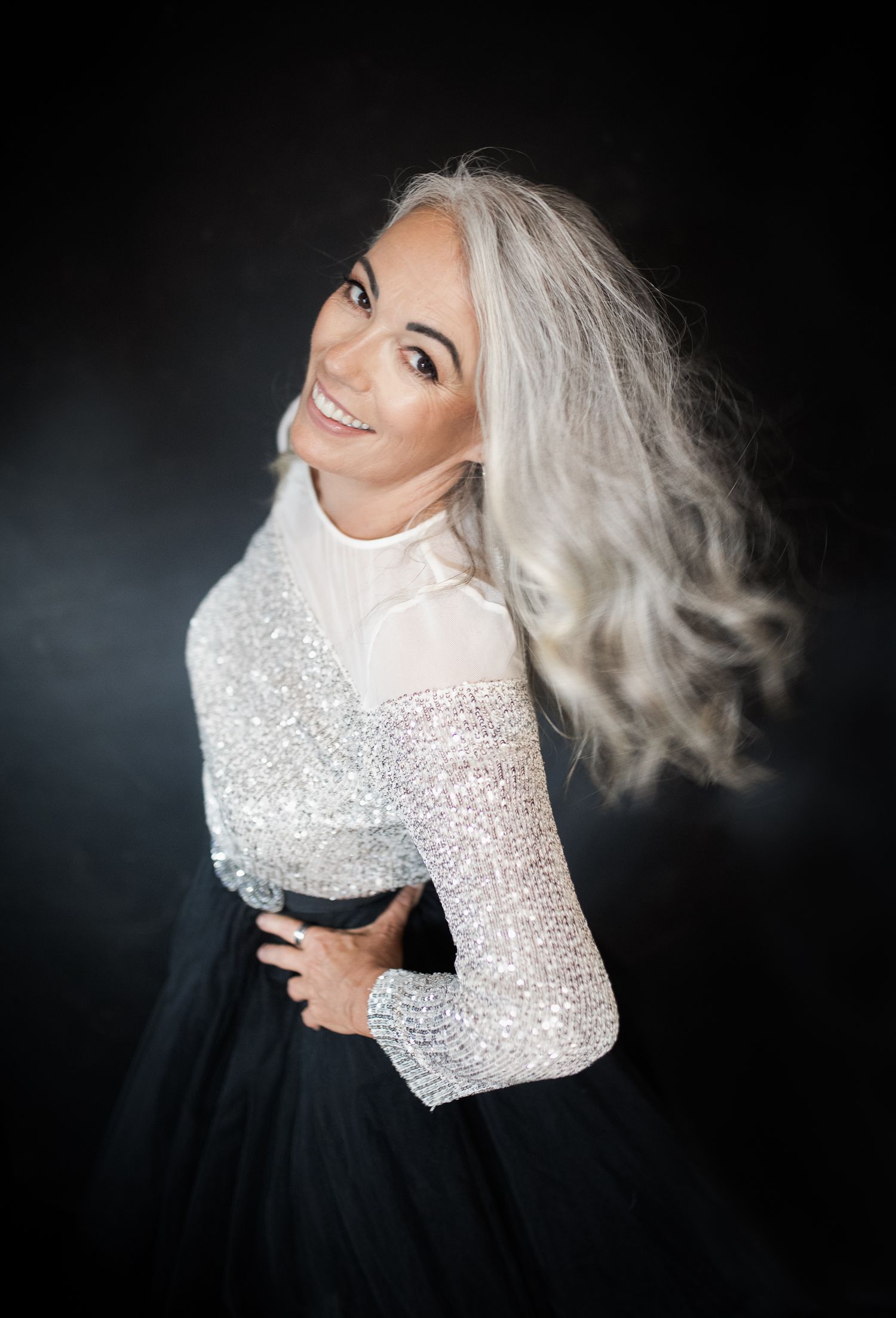 Dynamic fashion shots of a model in sparkling white top and black skirt with flowing platinum hair.
