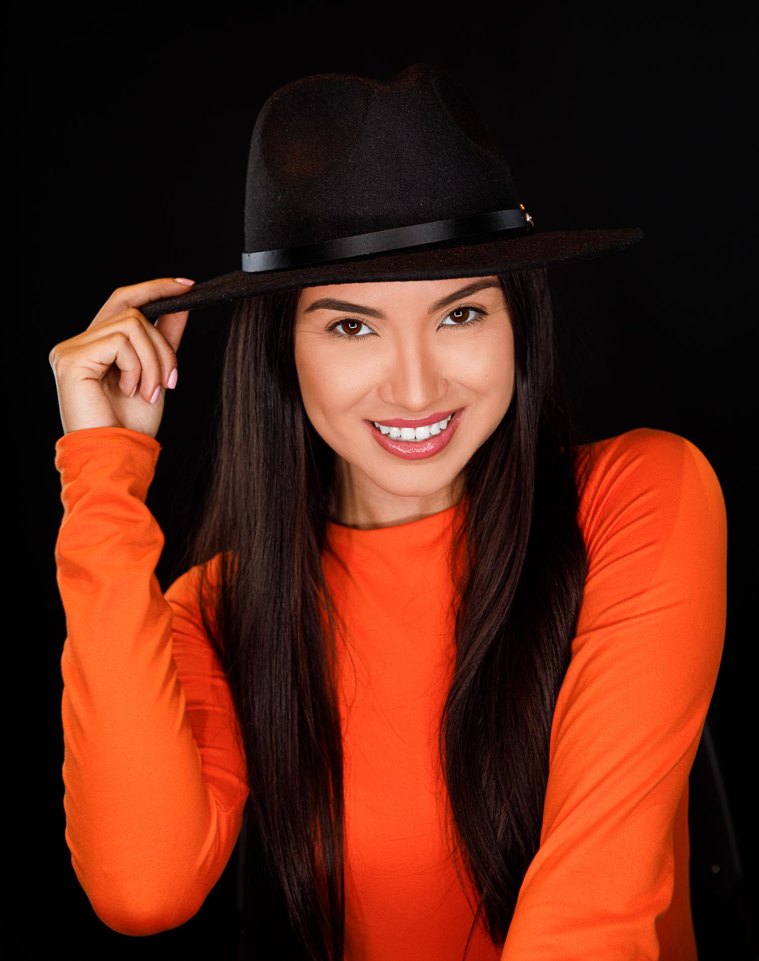 Dynamic fashion series showing joyful expressions in orange top and black hat.