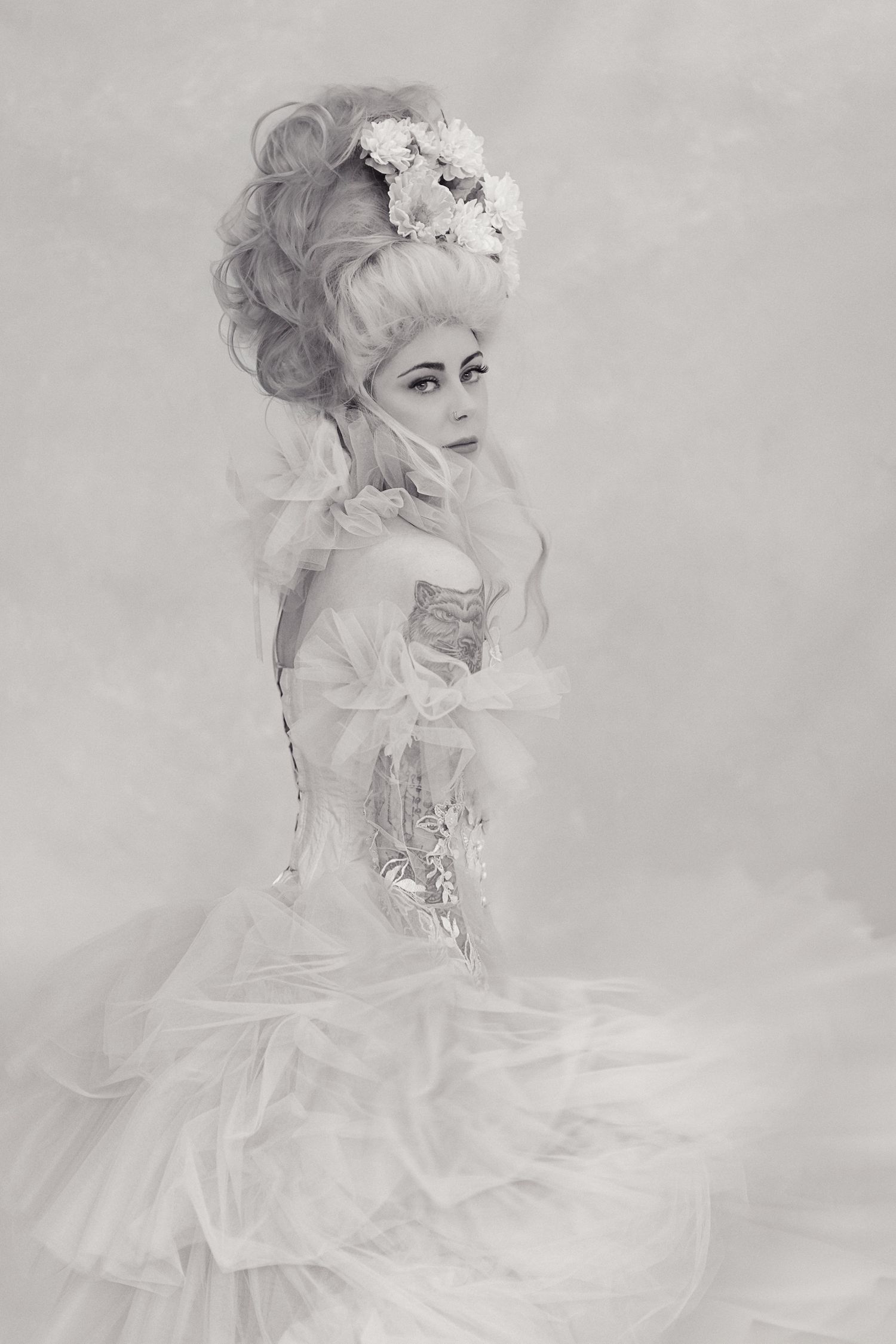 Ethereal portraits in soft gray tones featuring delicate white dress and floral hair accessories.