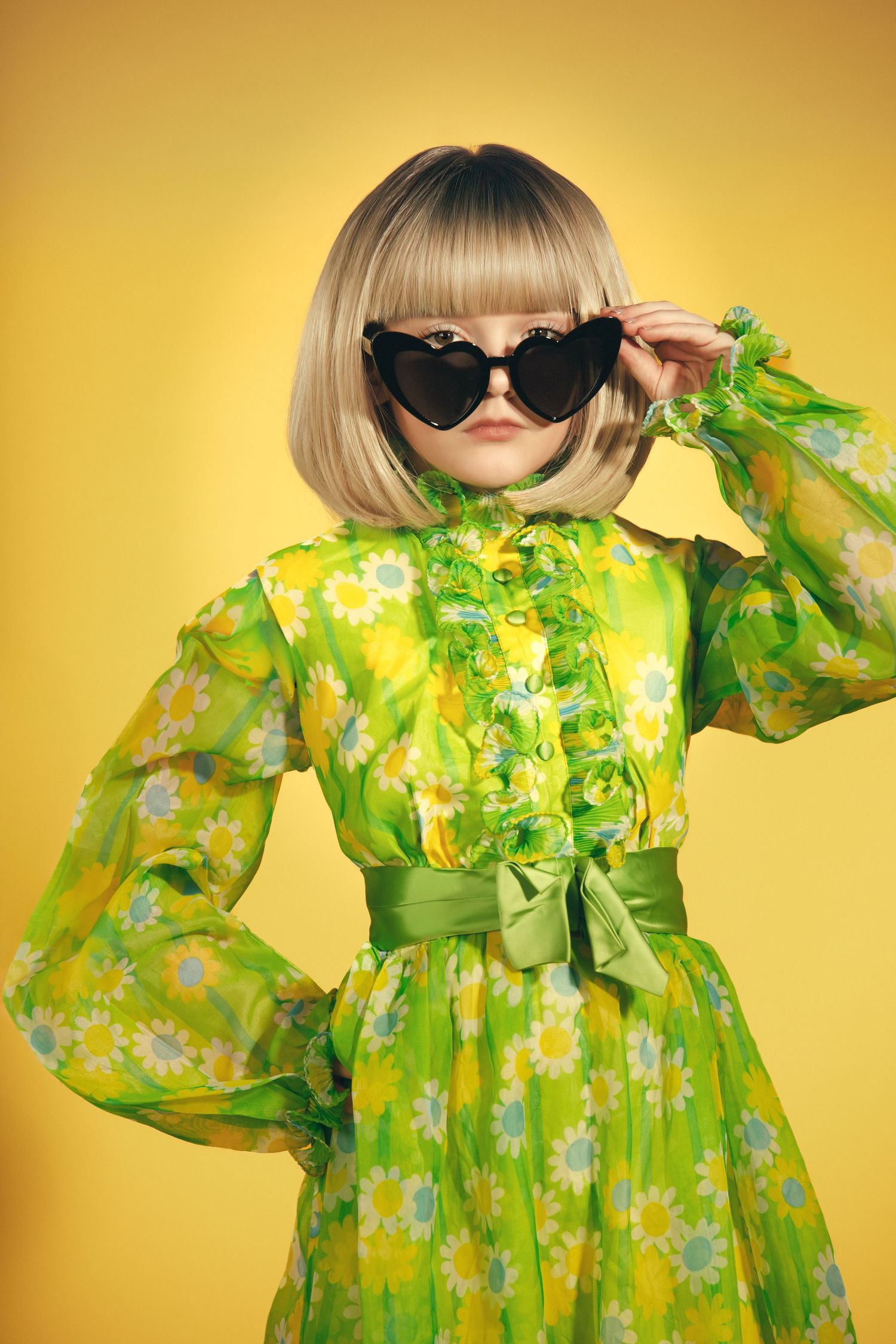 Artistic fashion series with a green floral dress and sunglasses against a vibrant yellow backdrop.