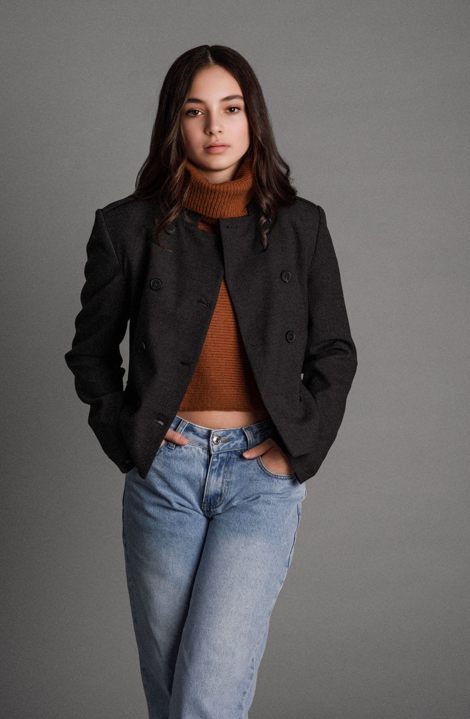 Fashion editorial shot featuring black jacket, brown turtleneck and classic blue jeans.