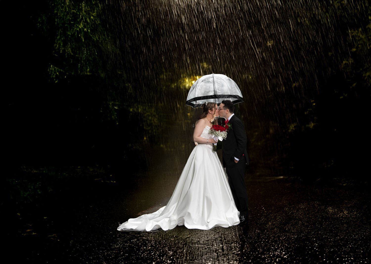 Bride and groom kissing under an umbrella in the rain. Creative Toronto wedding photography in any weather.