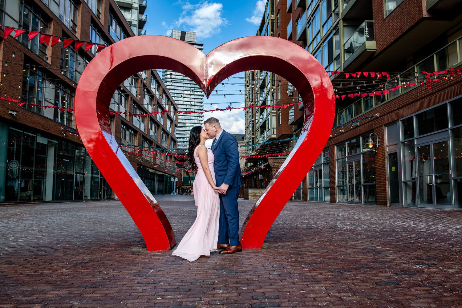 Romantic engagement photos at Toronto Distillery District featuring a couple inside a heart sculpture.