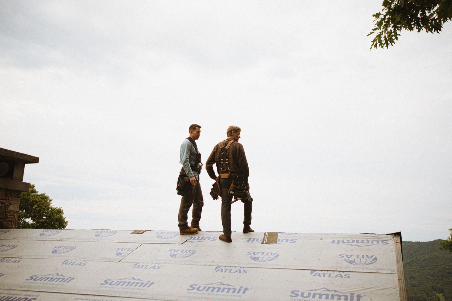 Two roofers standing on a roof covered with Atlas Summit underlayment during a residential roofing installation project.