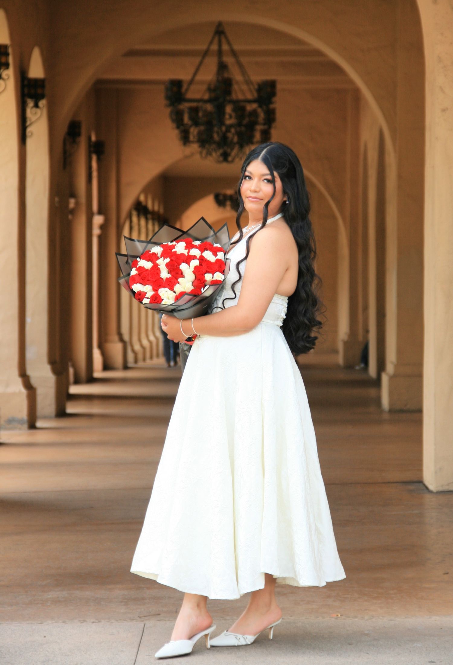 Woman in white dress holding holiday gift box at Balboa Park | Nuvue Visuals holiday portrait photography in San Diego