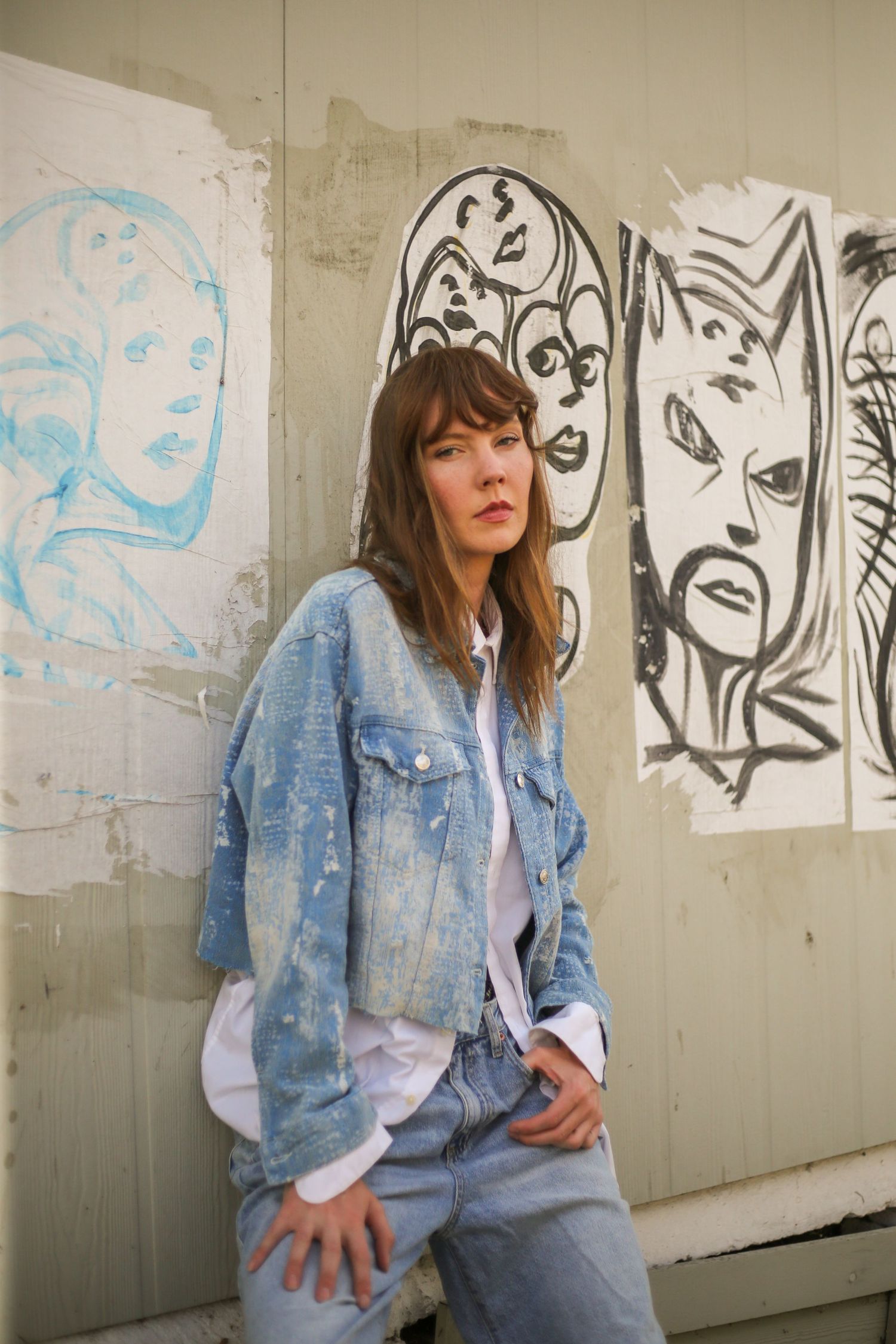 Young woman in denim outfit sitting by mural wall | Nuvue Visuals creative portrait photography in Los Angeles