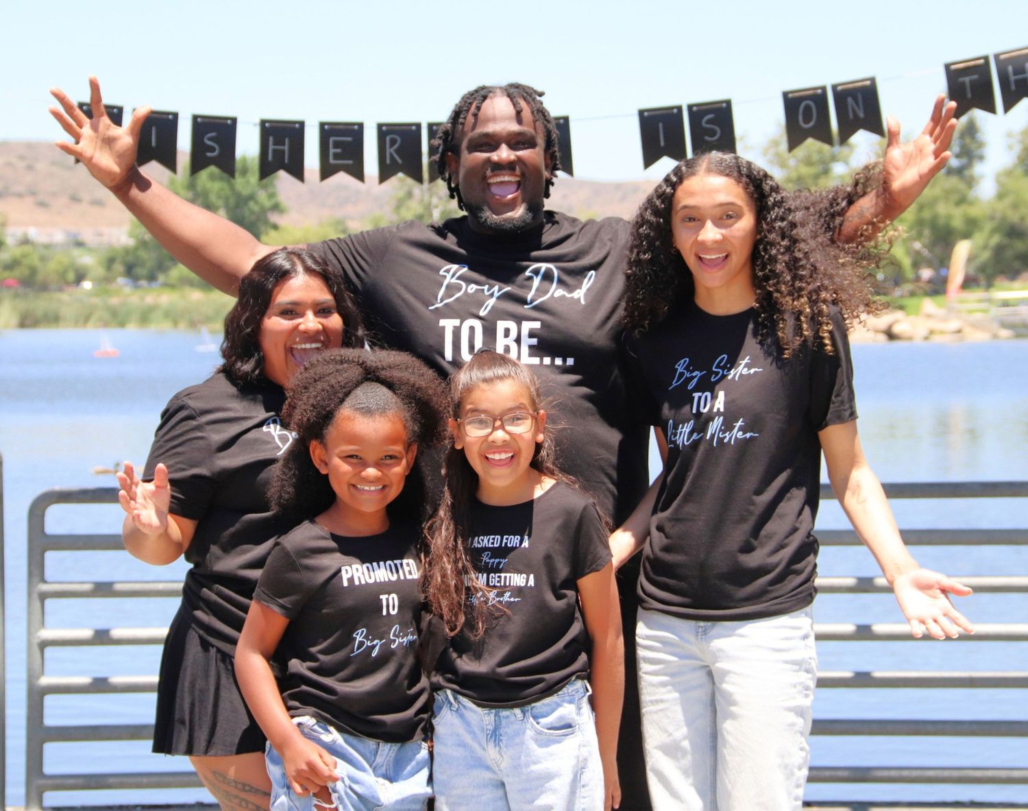Family smiling together outdoors near the water | Nuvue Visuals family photography in San Diego Baby reveal sursprise Santee lakes