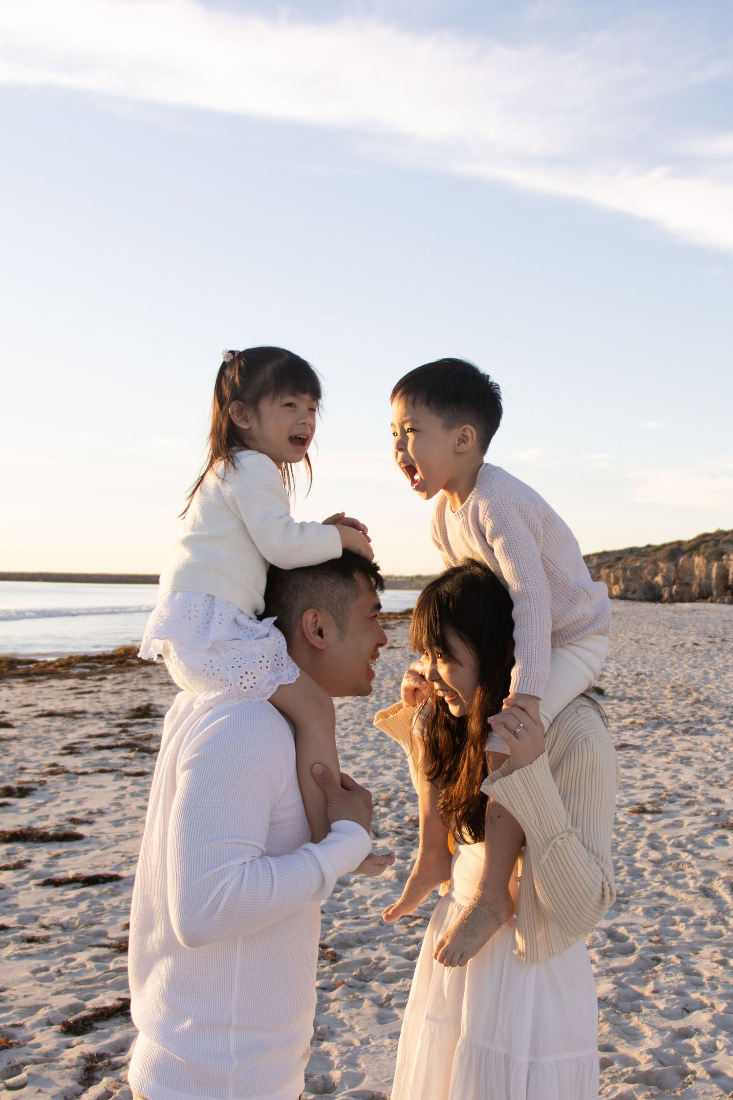 Young family running, cuddling and laughing together during a fun outdoor family photography session in Perth.
