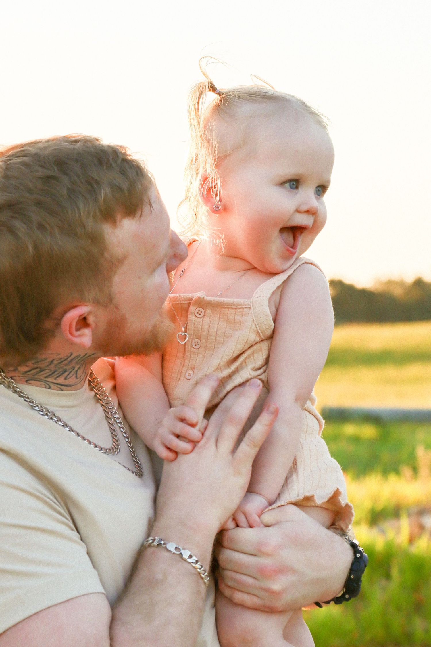 Father and daughter laughing in a field at a candid family photoshoot in Perth.