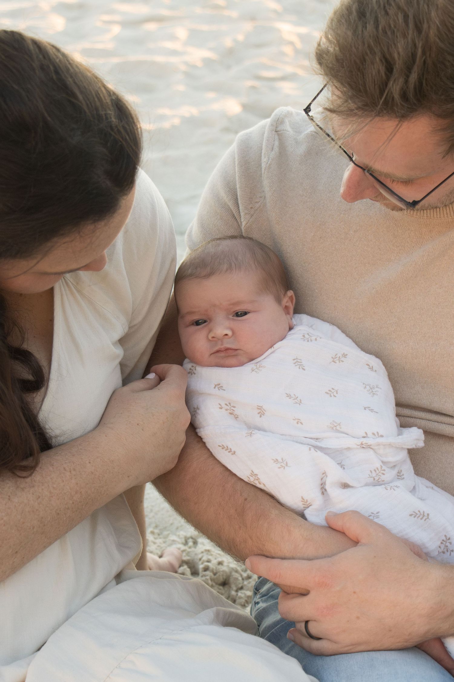 Parents cuddling their newborn baby outdoors during a relaxed lifestyle newborn photography session in Perth.