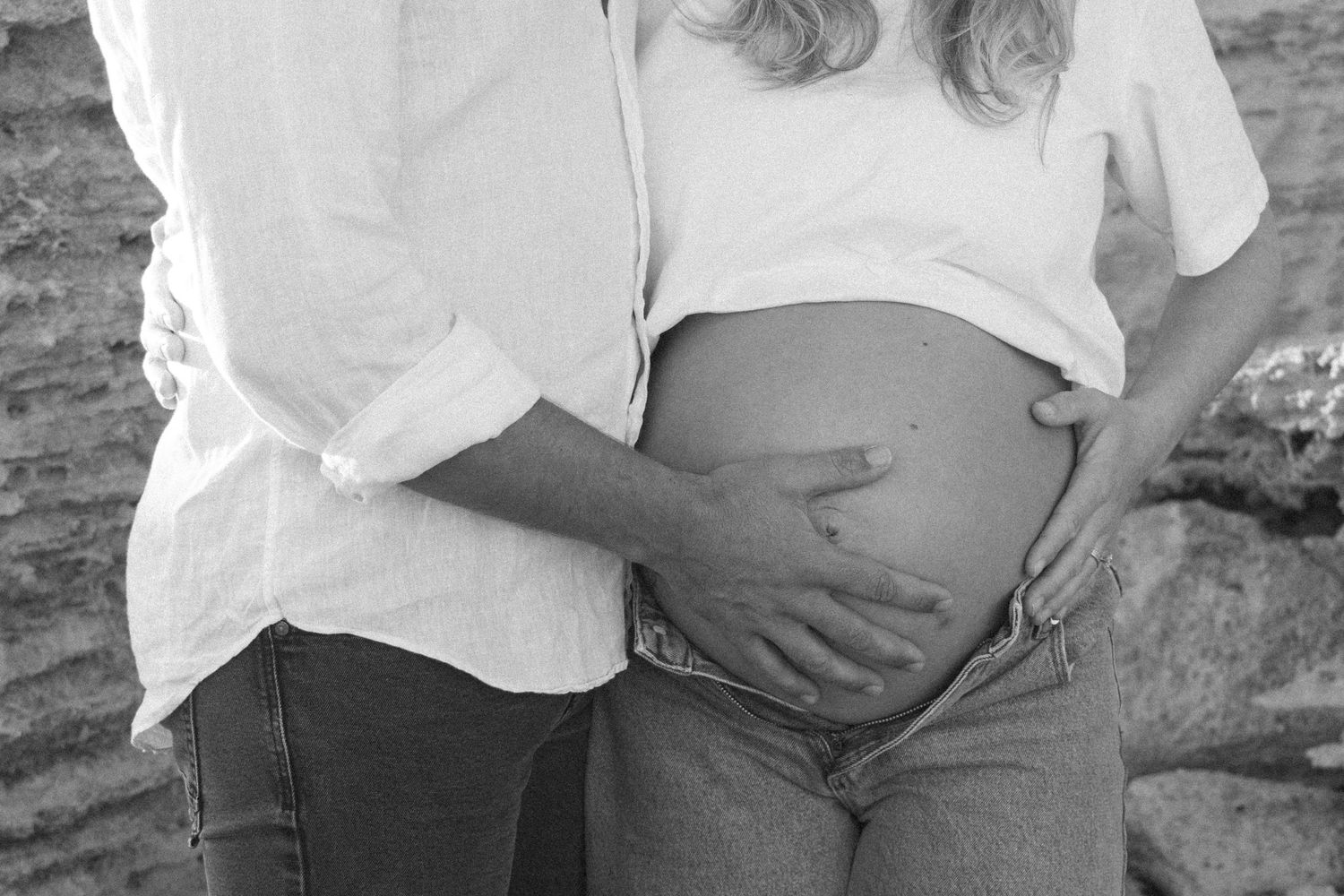 Couple celebrating their pregnancy announcement with natural, candid photos at a Perth beach during golden hour.