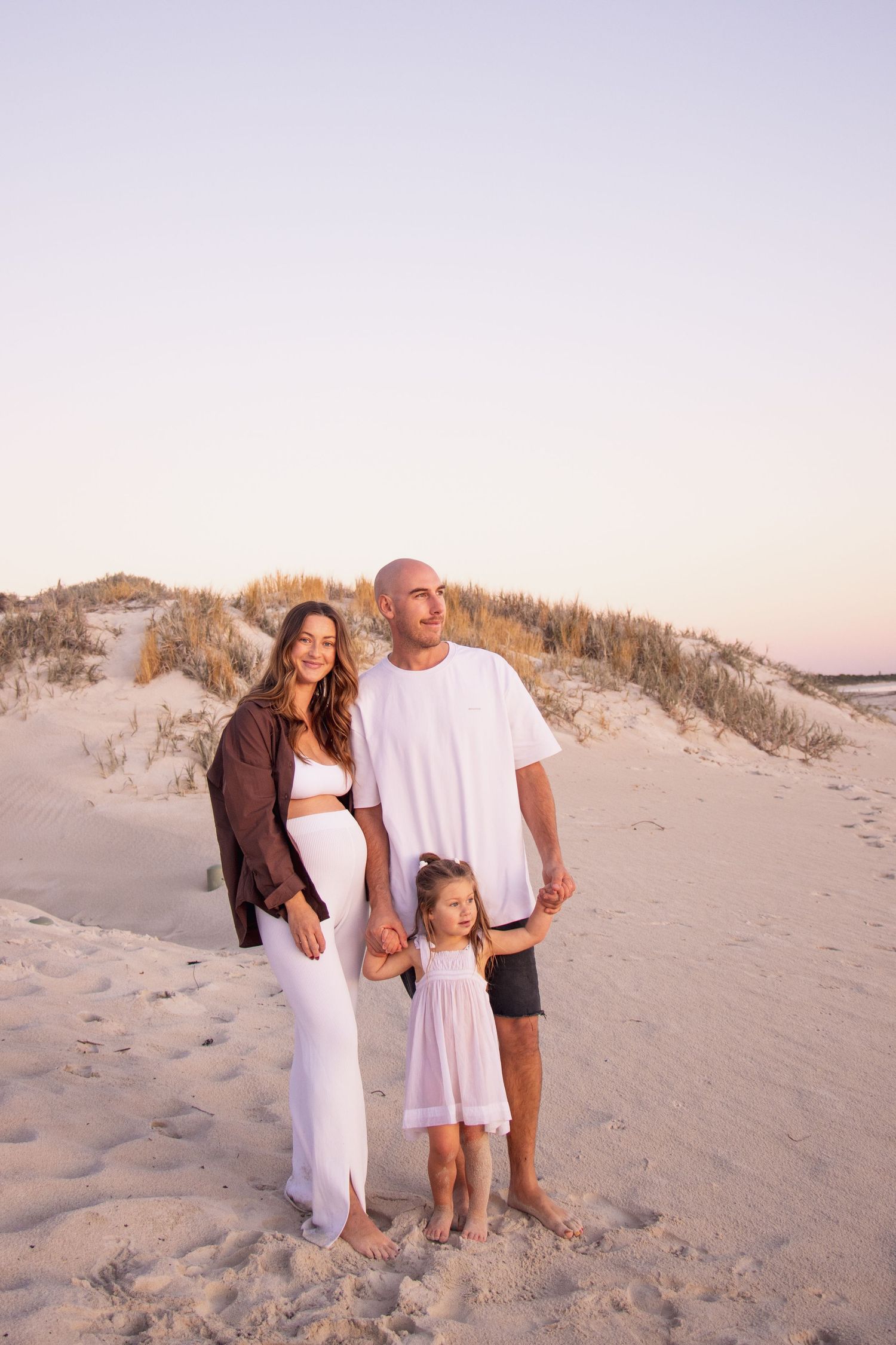 Family looking out to the sunset during a candid family photography session at the beach.