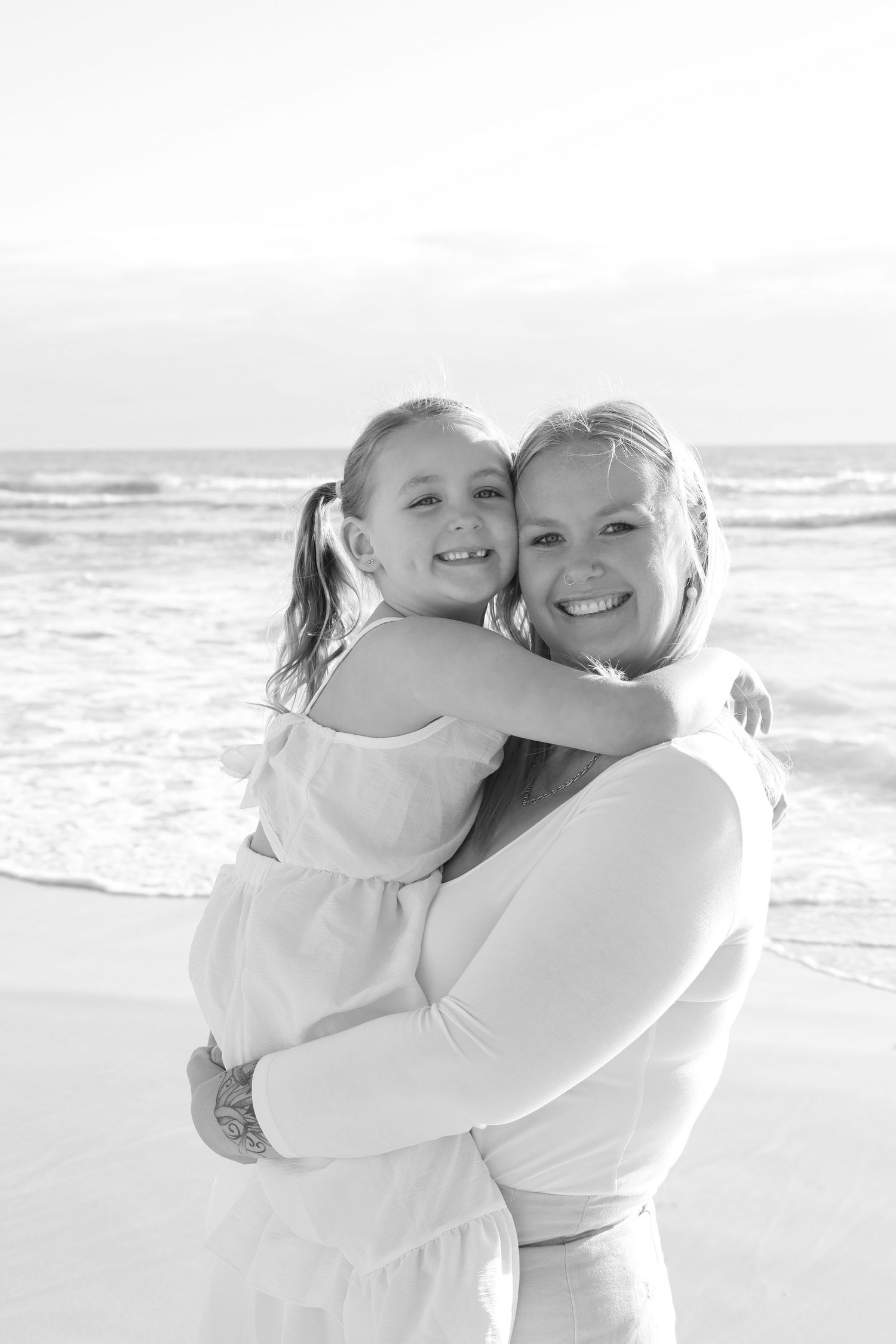 Mum cuddling her little girl while watching the sunset during a candid outdoor family photography session in Perth.