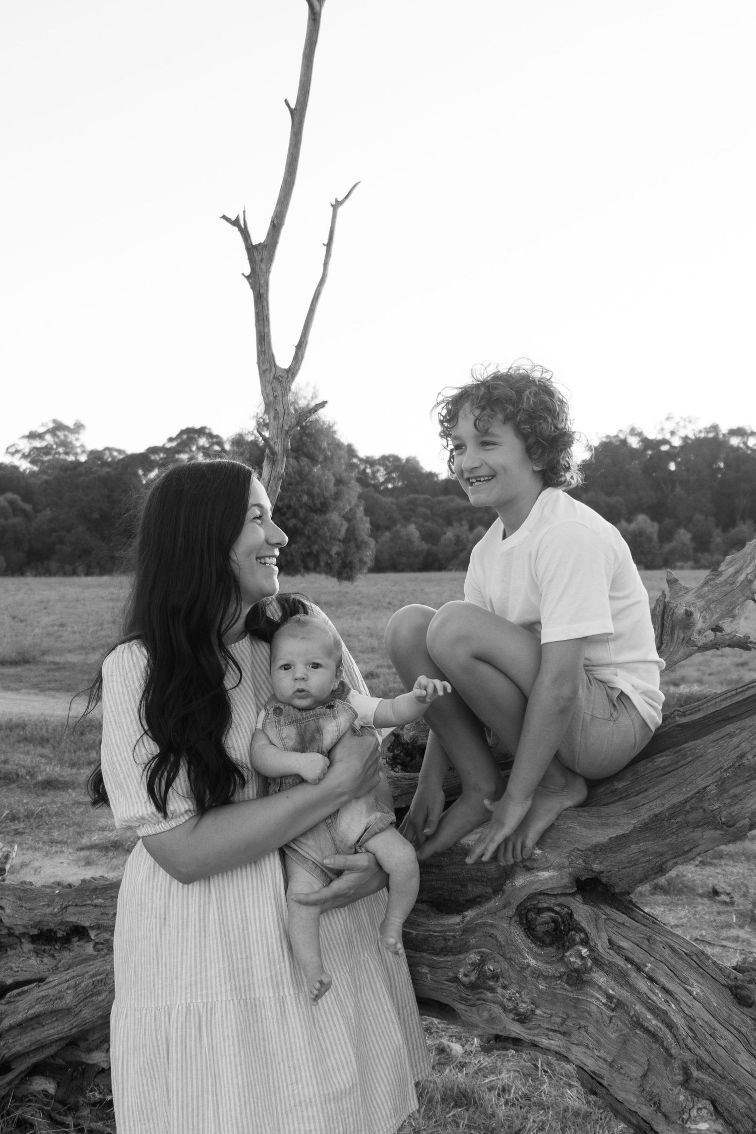 Family laughing together in a field at sunset during a candid family photography session.