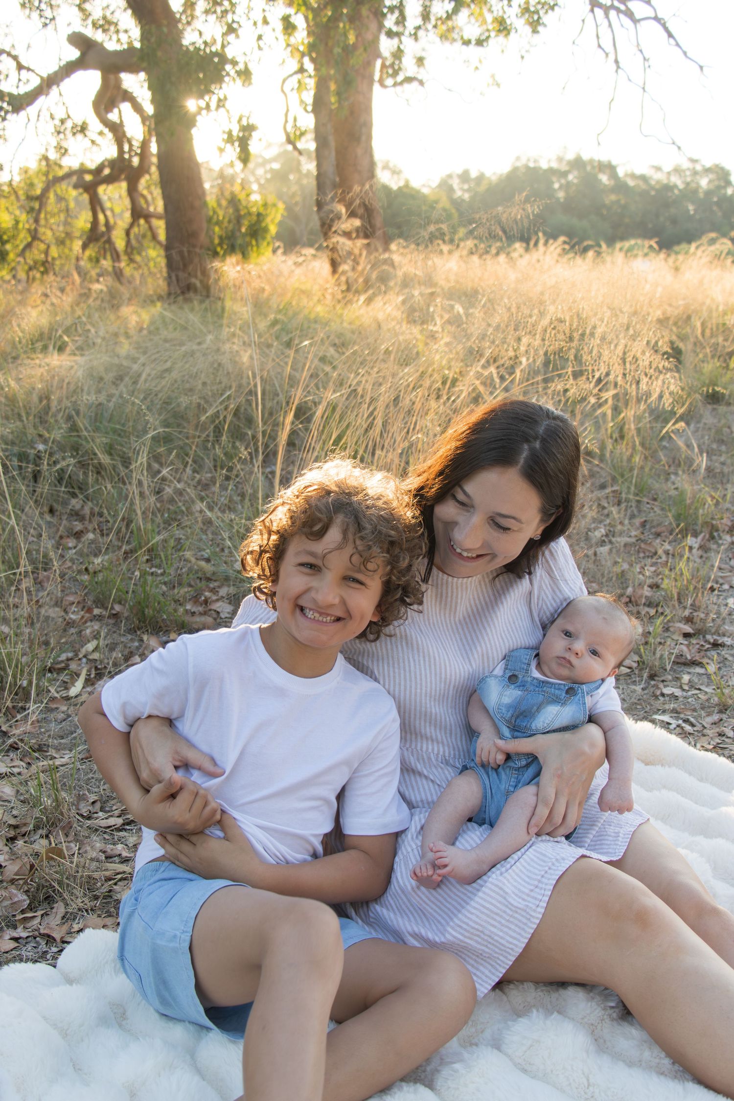 Family laughing together in a field at sunset during a candid family photography session.