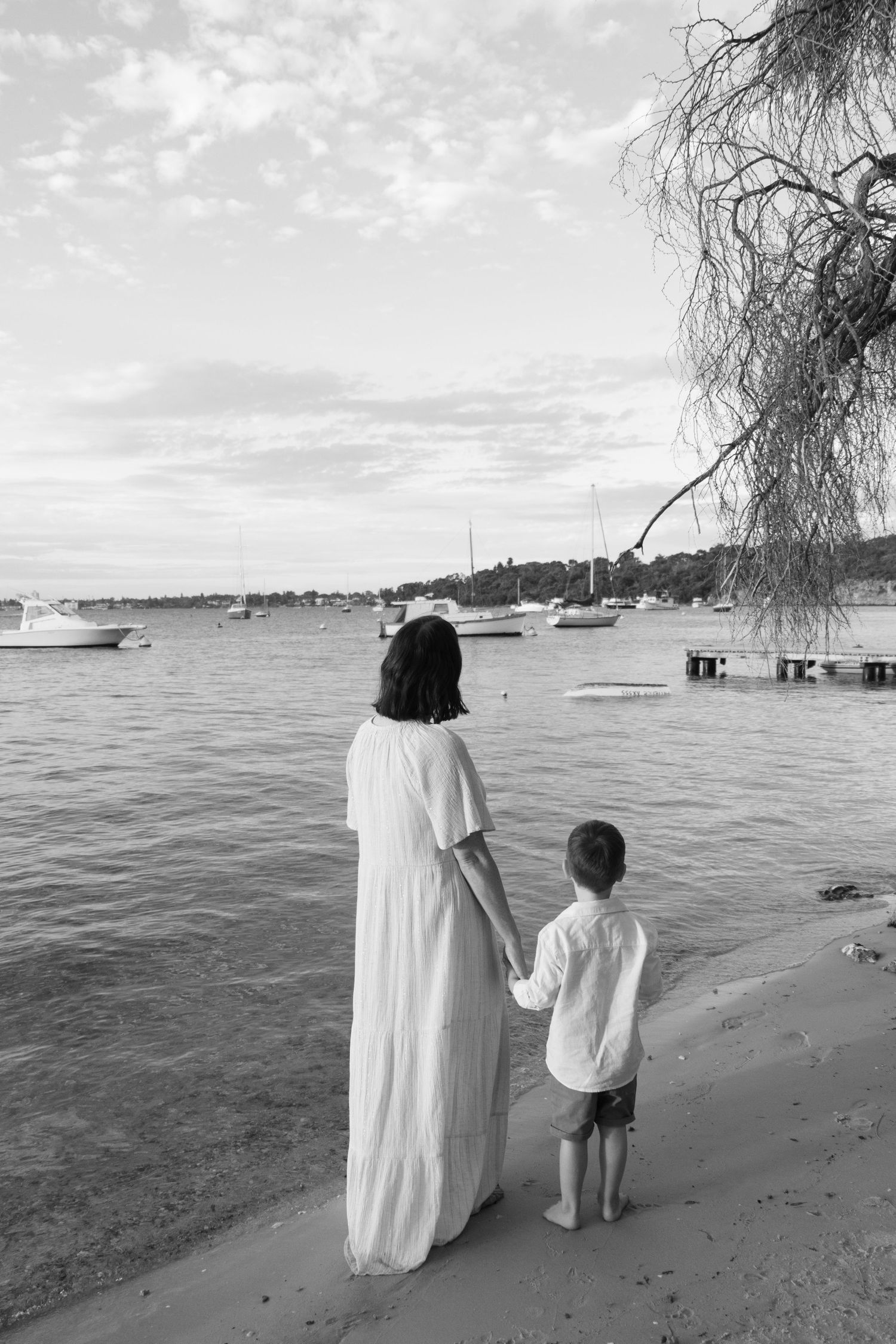 Mum and son looking out to boats on the river at sunset during a candid family photography session in Perth.