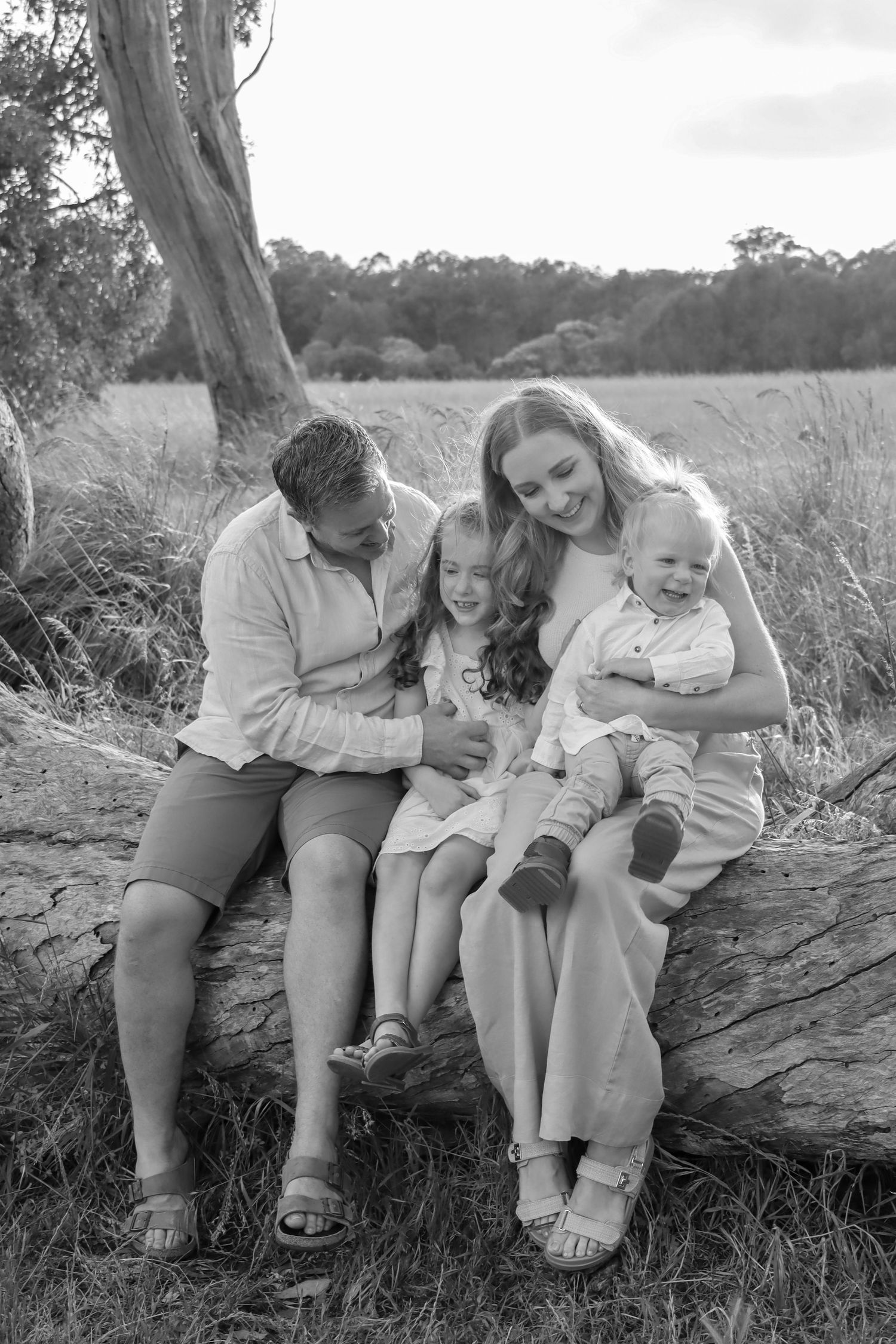 Family laughing together in a field at sunset during a candid family photography session.