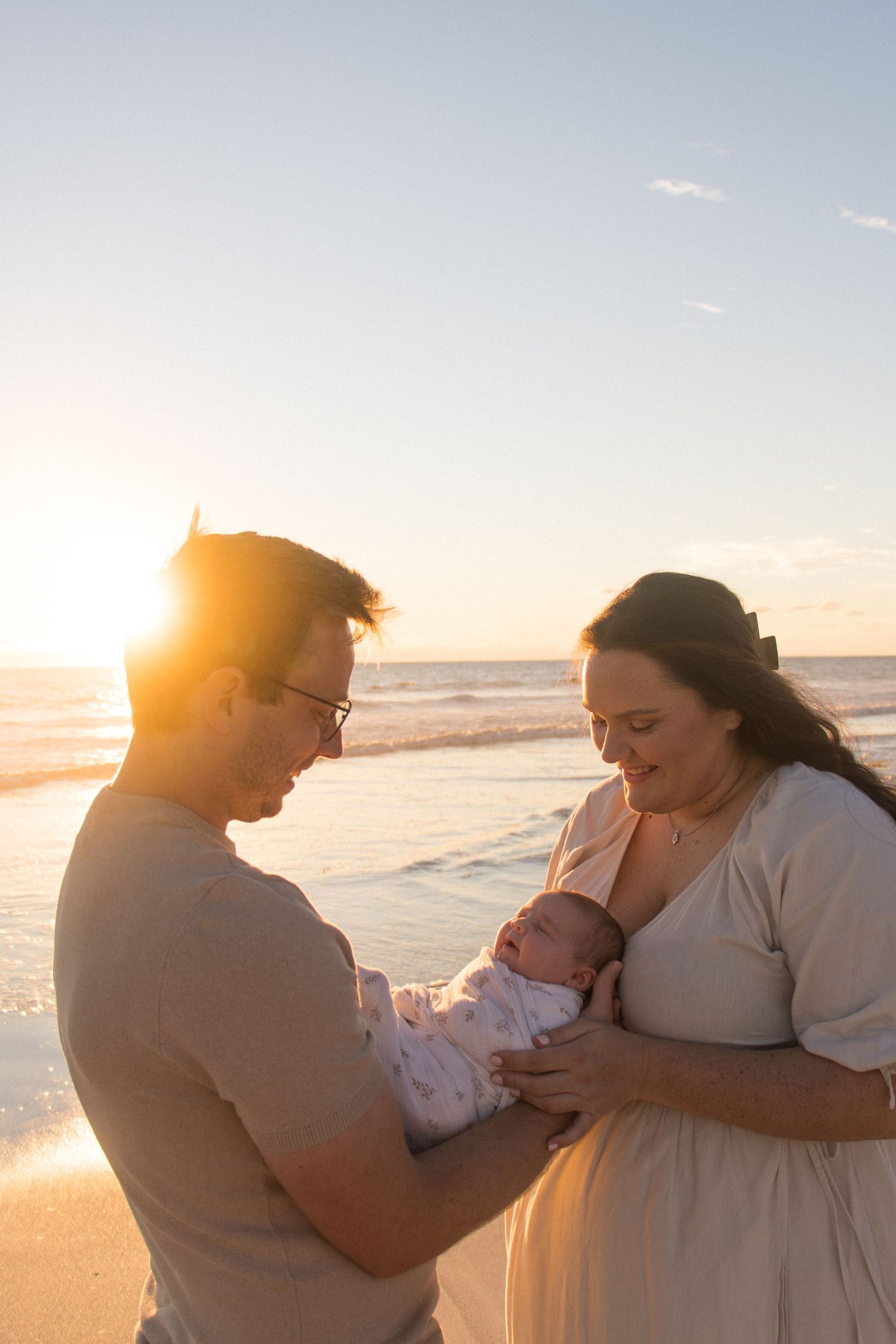 Parents cuddling their newborn baby outdoors during a relaxed lifestyle newborn photography session in Perth.