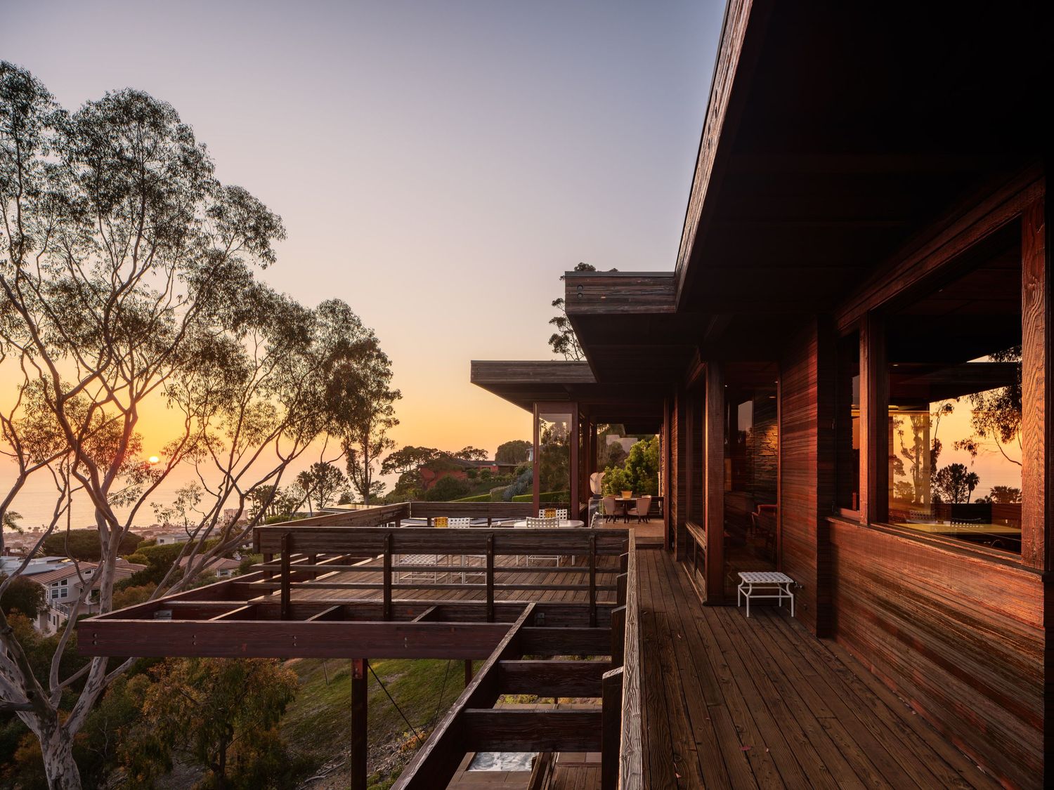 Sunset view along the deck of 7226 Romero, a midcentury La Jolla luxury home overlooking the ocean and framed by eucalyptus trees.