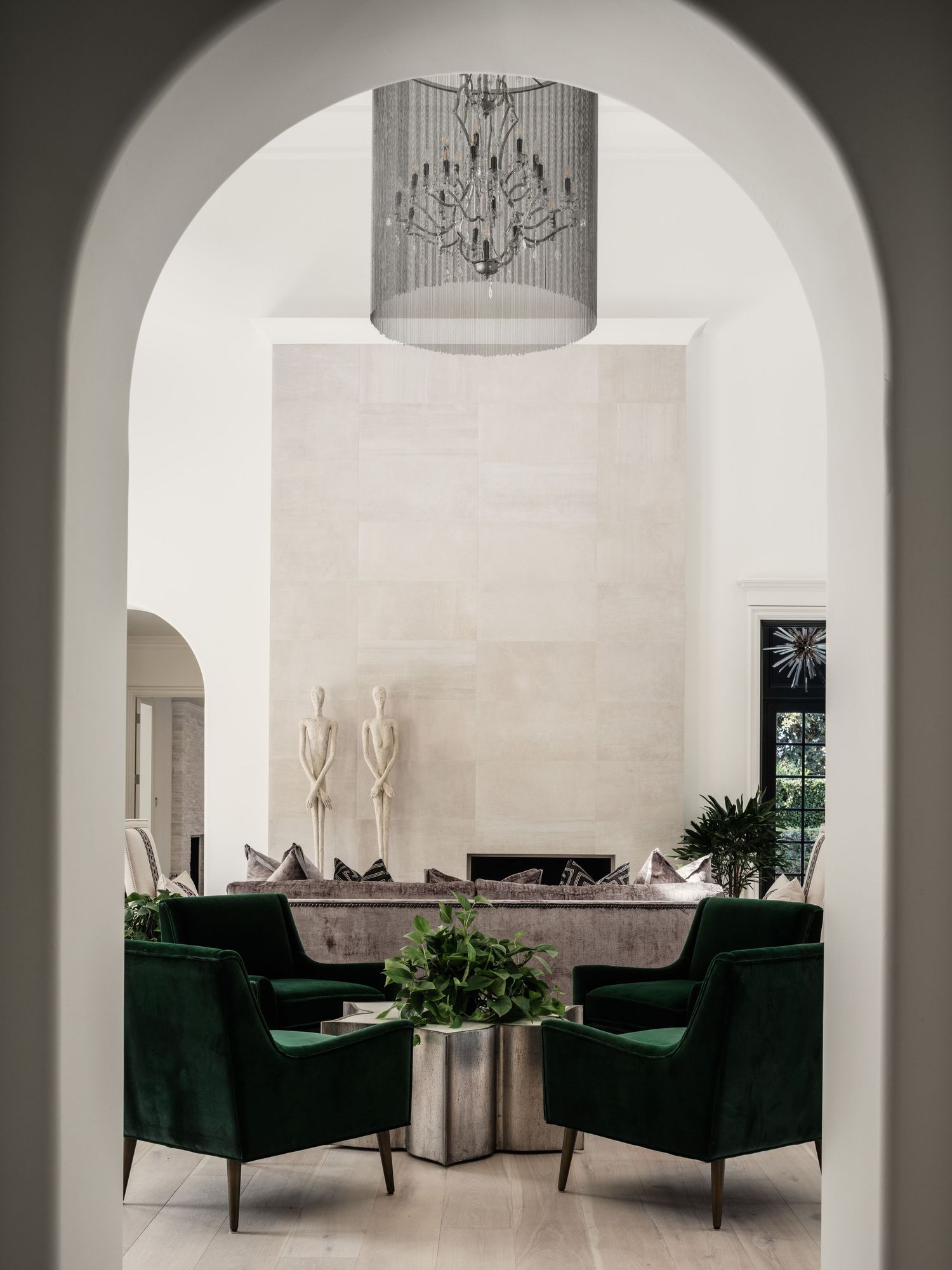 Arched entry frames Rancho Santa Fe luxury living room with green velvet chairs and chandelier—interior photography by Luca Prodi
