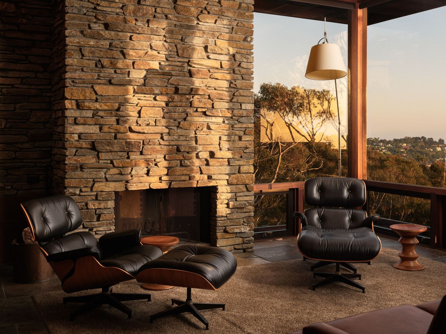 Stone fireplace and Eames lounge chairs at 7226 Romero, interior design photography san diego highlighting midcentury details.