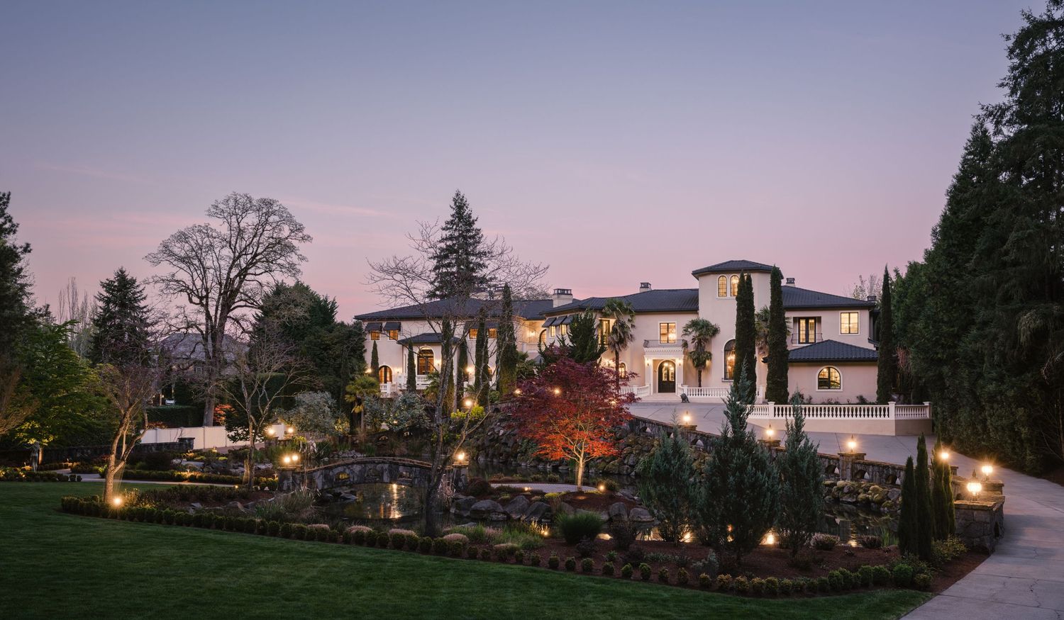 Twilight exterior photo of the Fielding House showing landscaped gardens, pond, and grand façade captured for a luxury real estate project.