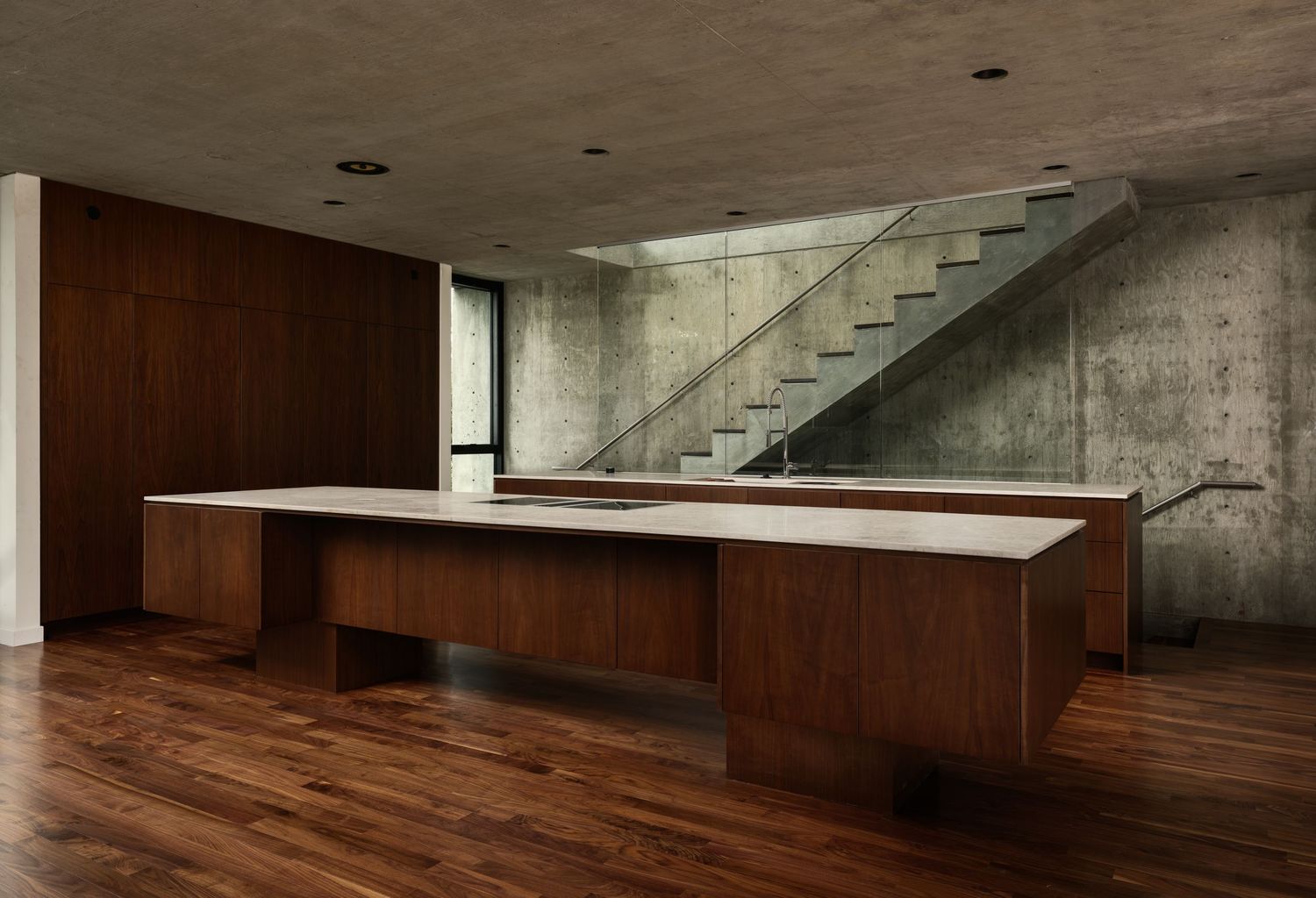Arista Residence kitchen interior by Matthew Segal, custom wood island, exposed concrete walls, and glass stair—architectural photography.