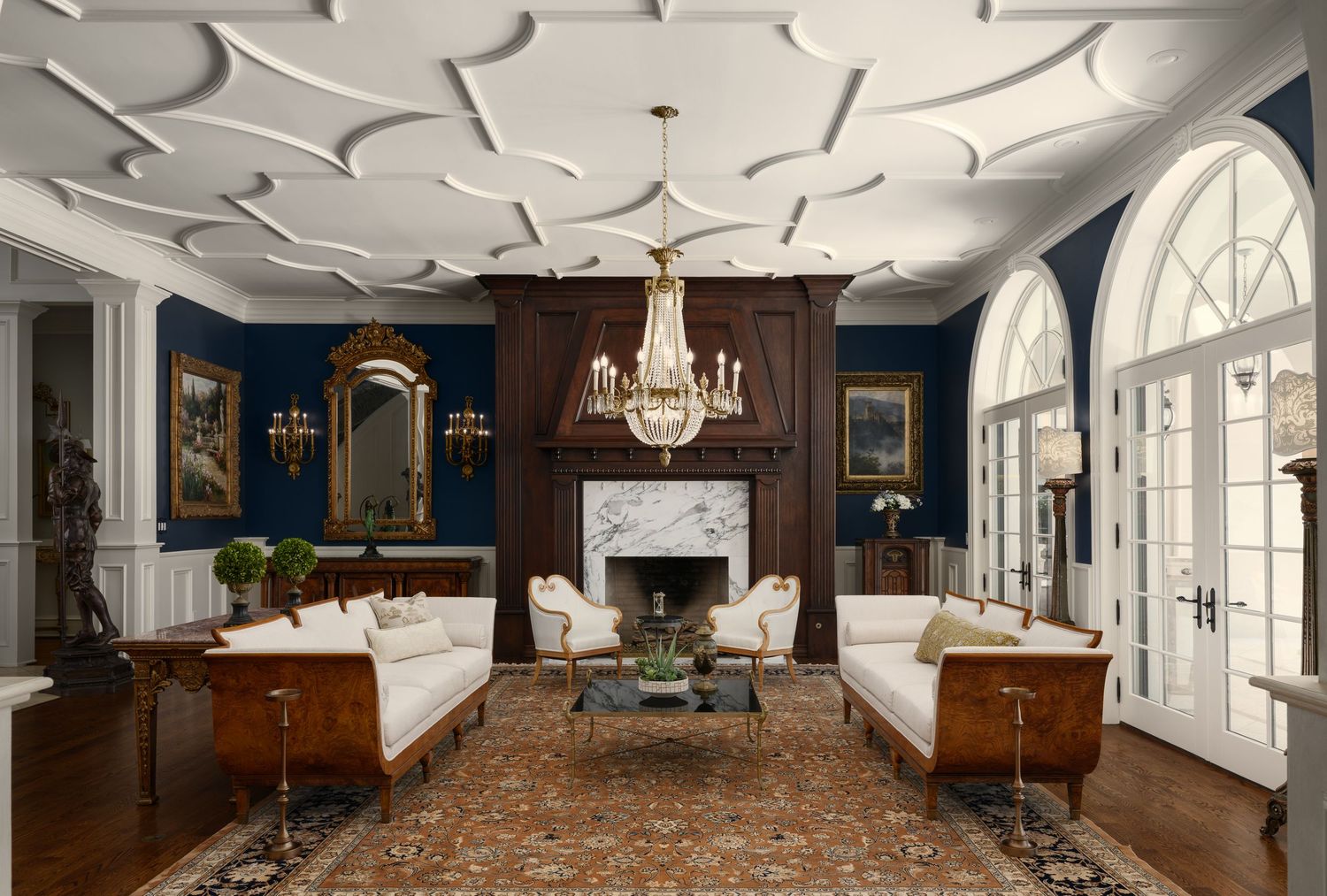 Elegant living room at Fielding House with coffered ceiling, marble fireplace, deep blue paneling, and refined classic interior design