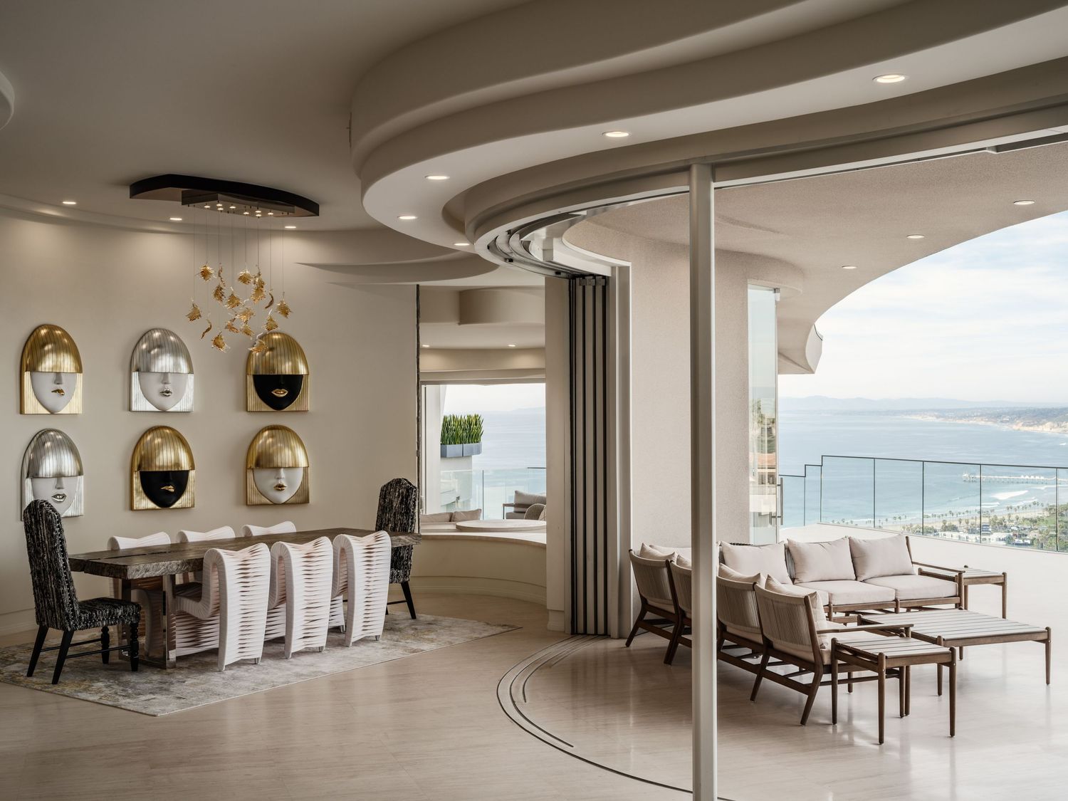 Curved open-plan living and dining space with sculptural ceiling, contemporary art, and expansive ocean-view terrace in a La Jolla hillside