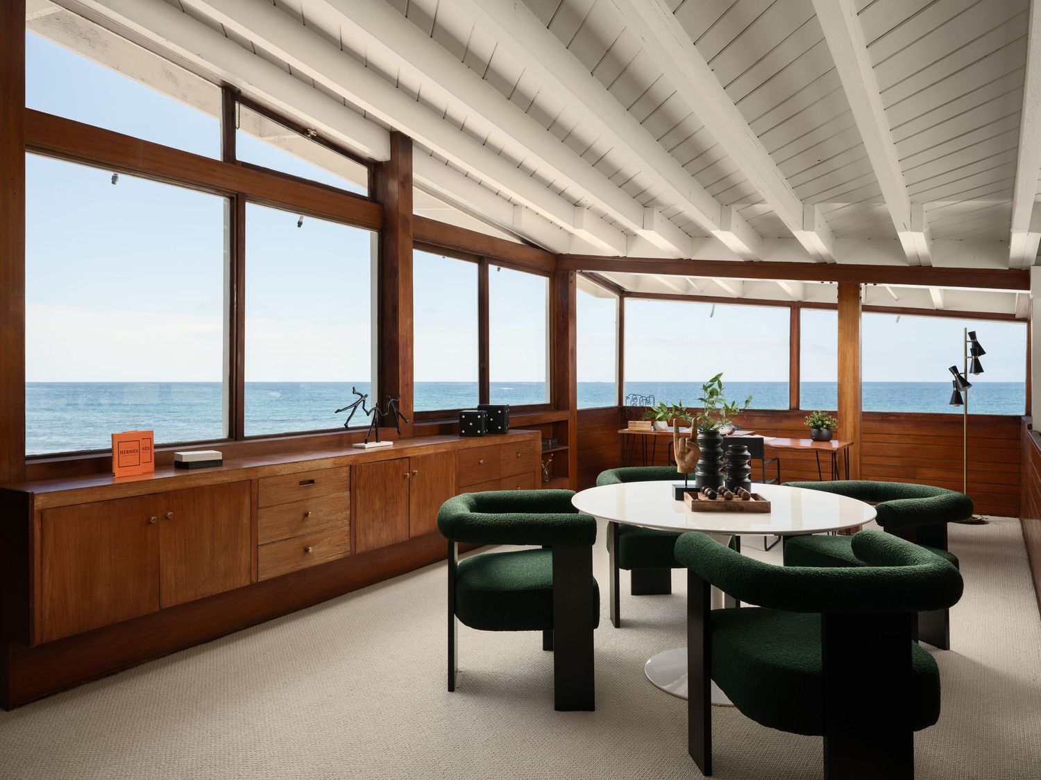 Midcentury coastal living and dining space at 1890 Spindrift Drive with exposed beams, built-ins, and panoramic Pacific Ocean views.