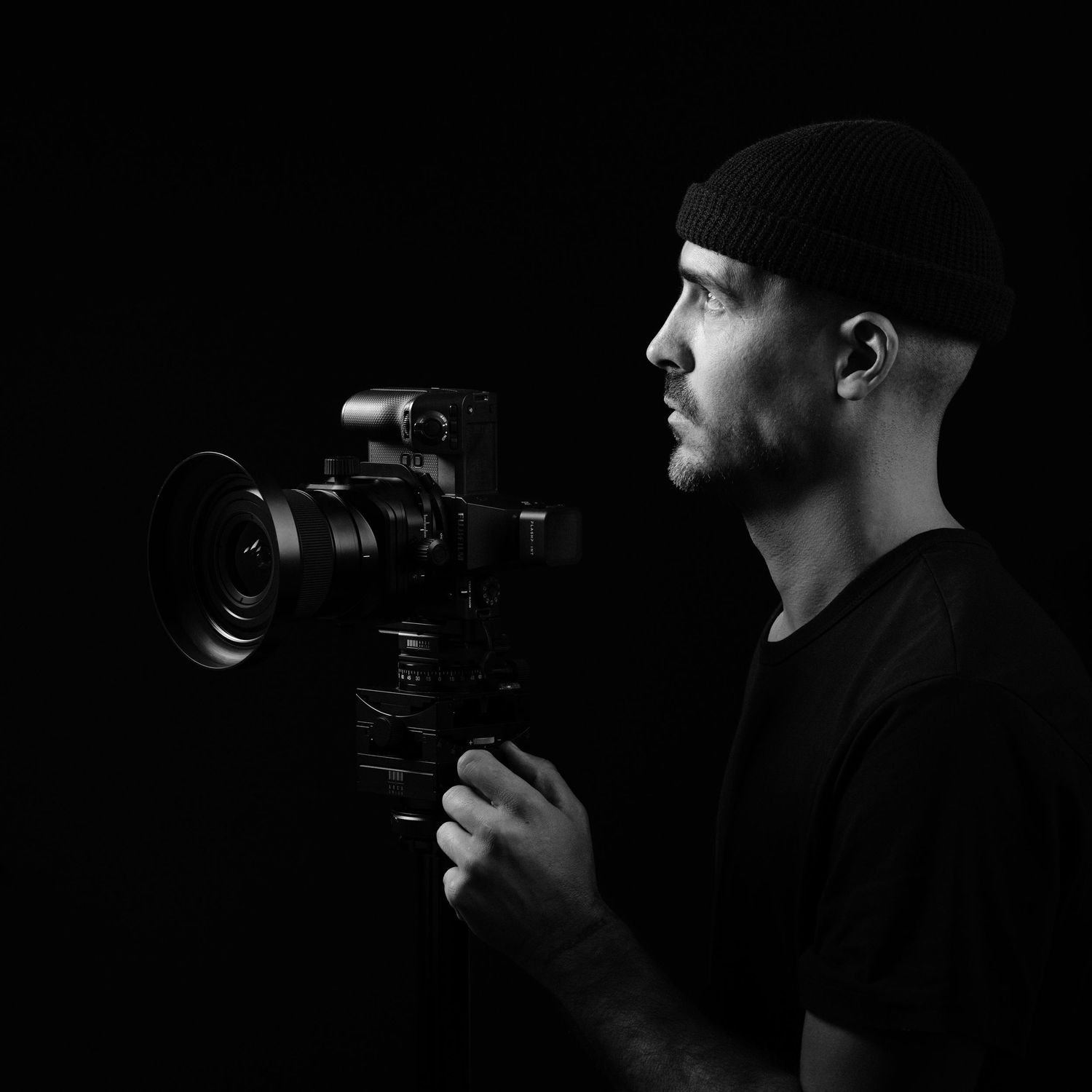 Portrait of Luca Prodi, architectural photographer, holding a camera in studio lighting.
