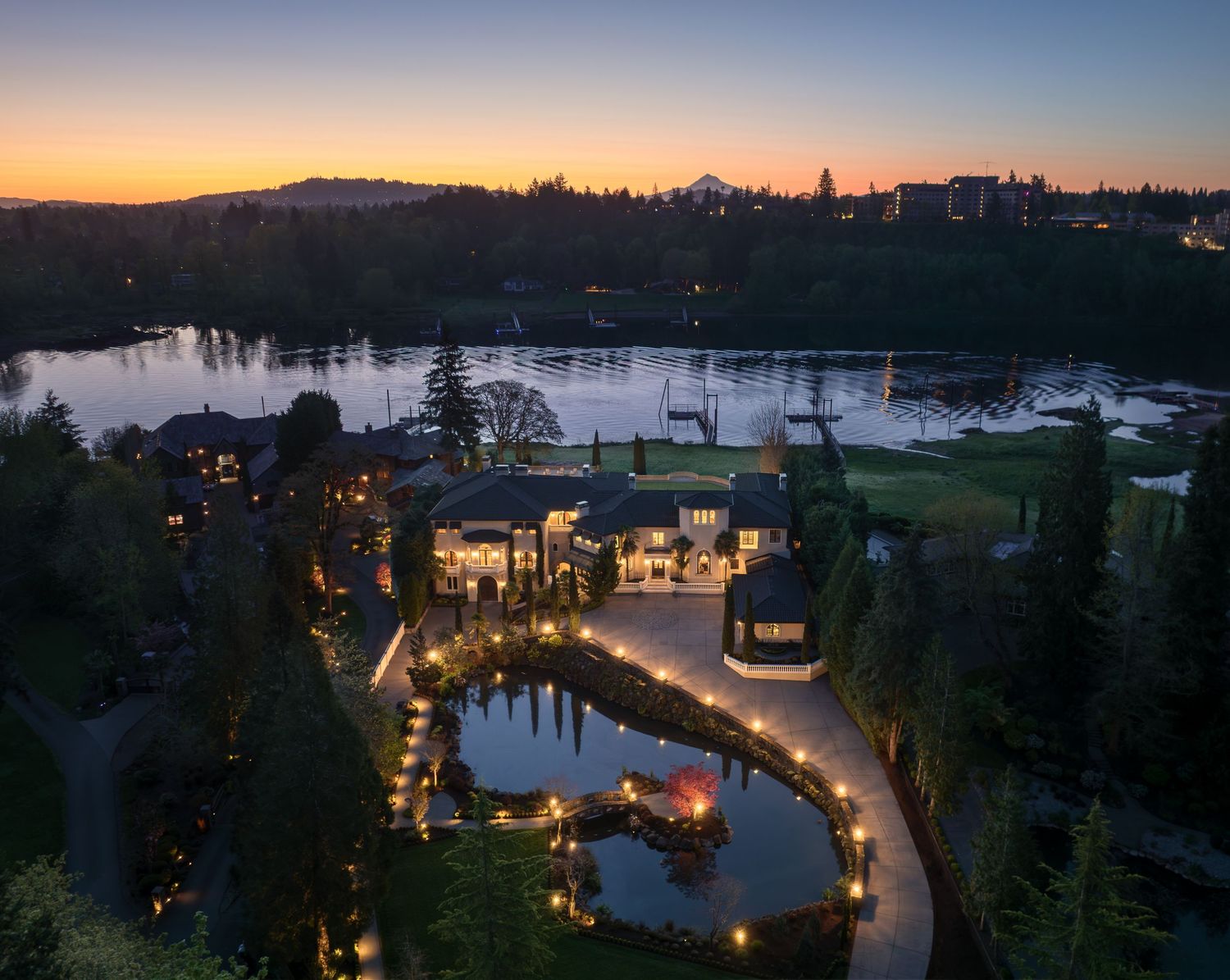 Twilight aerial of Fielding House capturing the estate’s lakeside setting, illuminated pathways, and grand architecture in Oregon