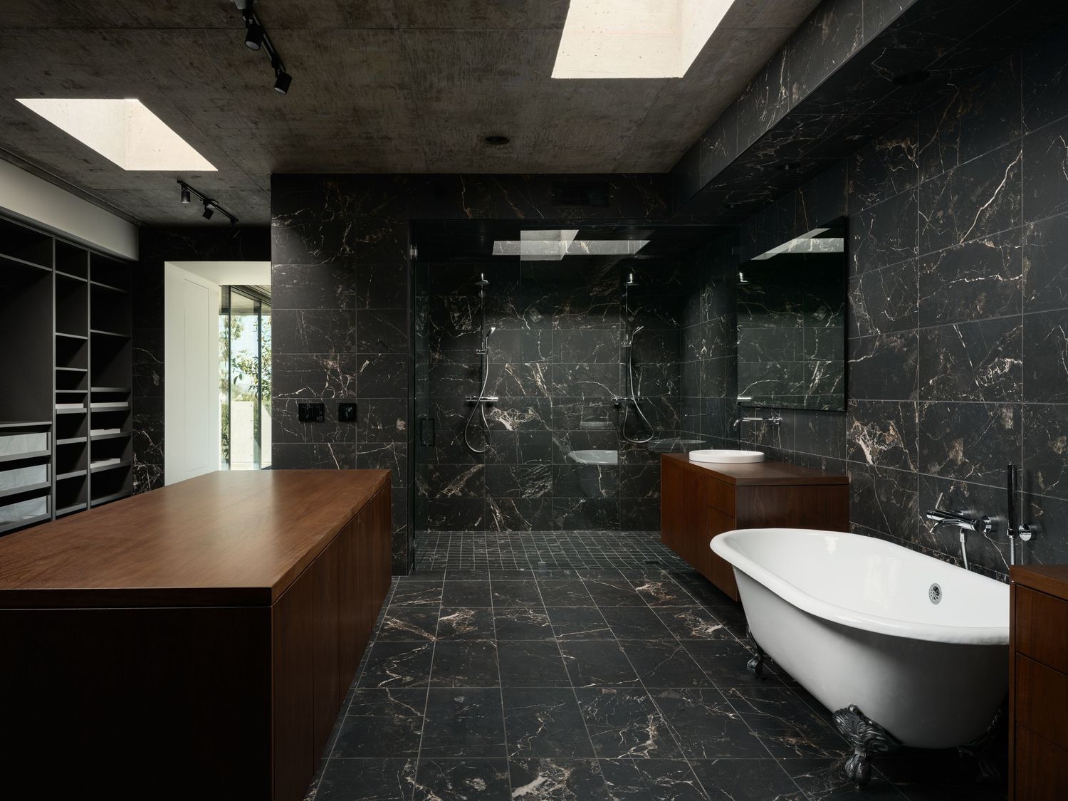 Arista Residence bathroom by Matthew Segal with freestanding tub, dark stone tile, wood cabinetry—architectural photo by Luca Prodi.