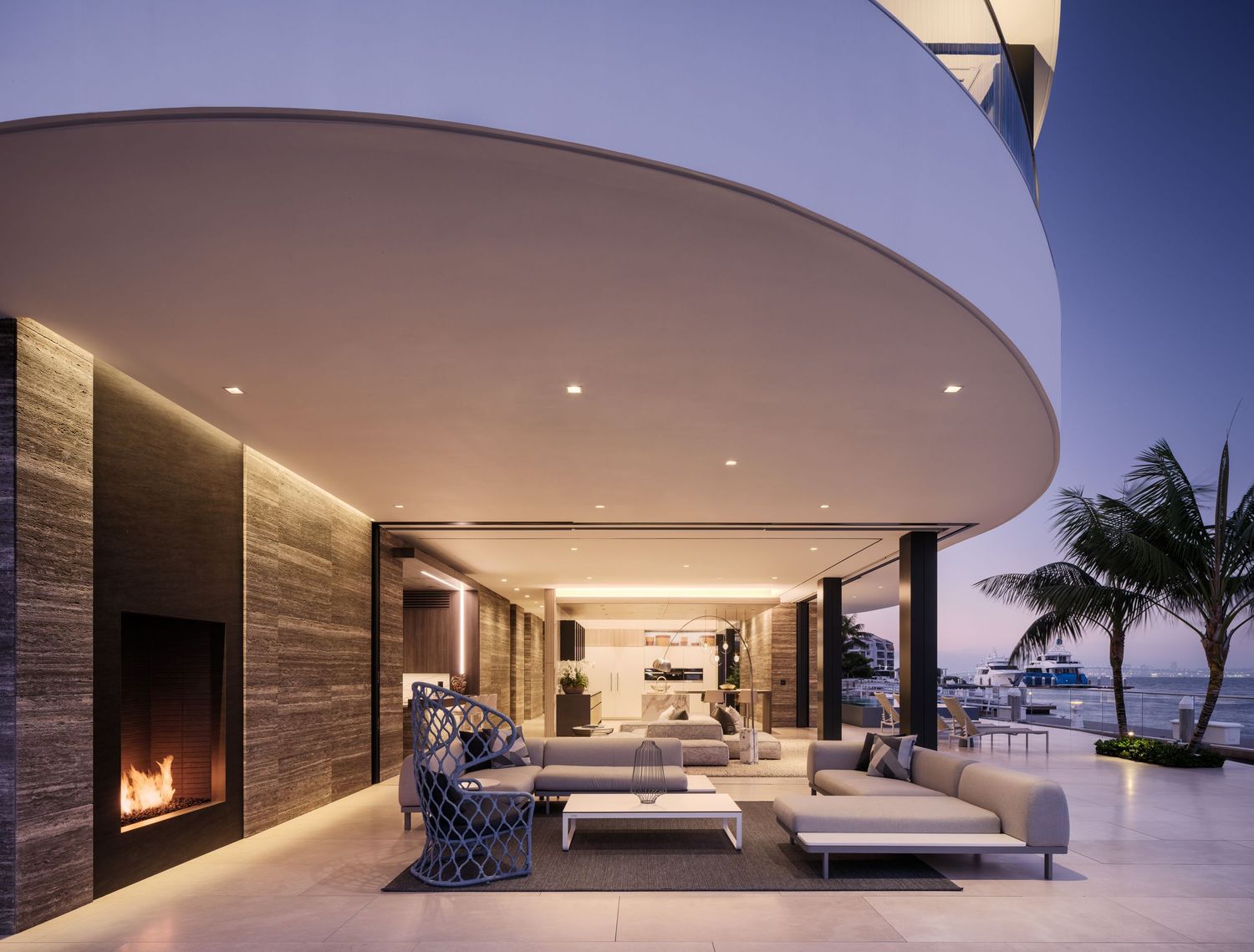 Covered outdoor living area at Coronado 3 The Point with fireplace, modern seating, and open-air waterfront design