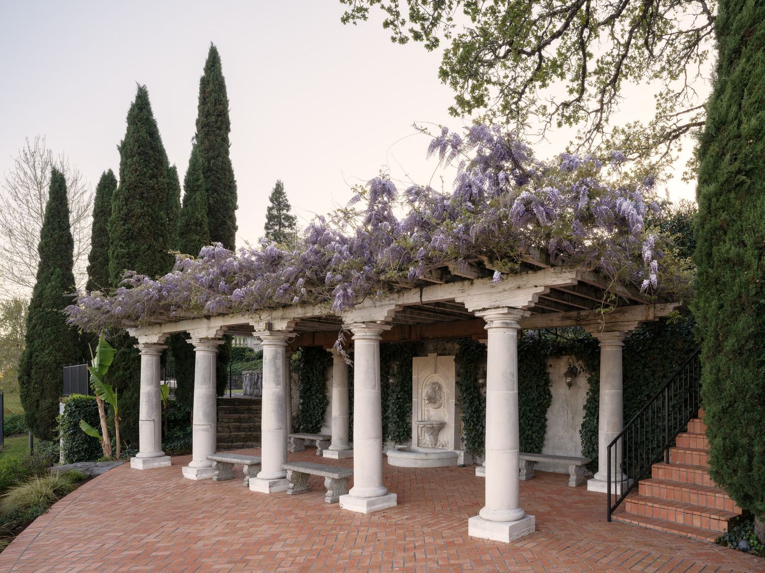 Wisteria-draped pergola at Fielding House, captured with architectural focus on columns, garden design, and evening light.