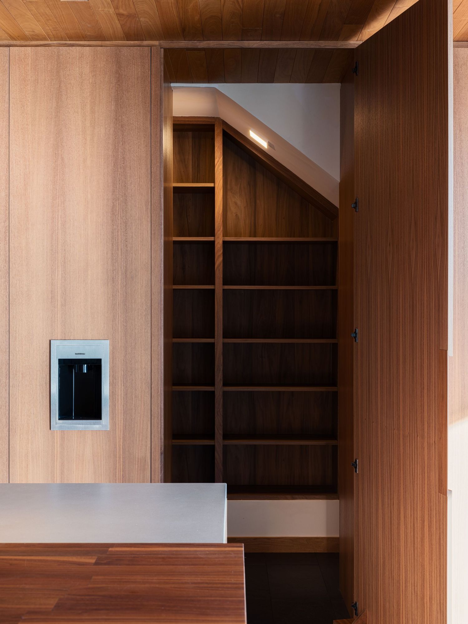 Custom wood storage and stair detail at 7003 Fay Avenue showcasing precise millwork and minimalist architectural detailing.