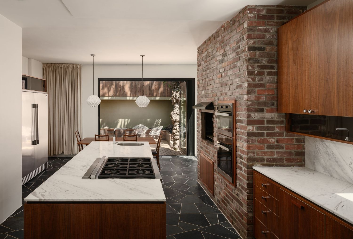 Chef’s kitchen with 10-foot Calacatta marble island, Miele appliances, brick wall and slate flooring at 2916 Chicago Street