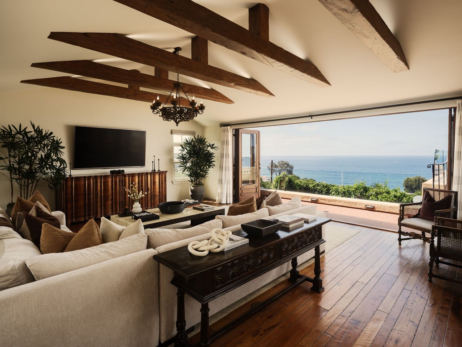 Luxury real estate interior at 7757 Whitefield featuring ocean-view living room, exposed beams, and natural light through retractable doors.