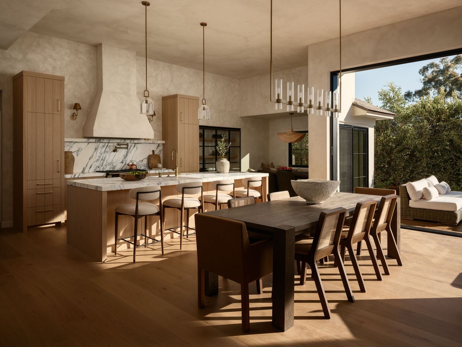 La Jolla luxury interior with limewash walls, custom marble kitchen island, wood cabinetry, modern lighting and indoor-outdoor dining design